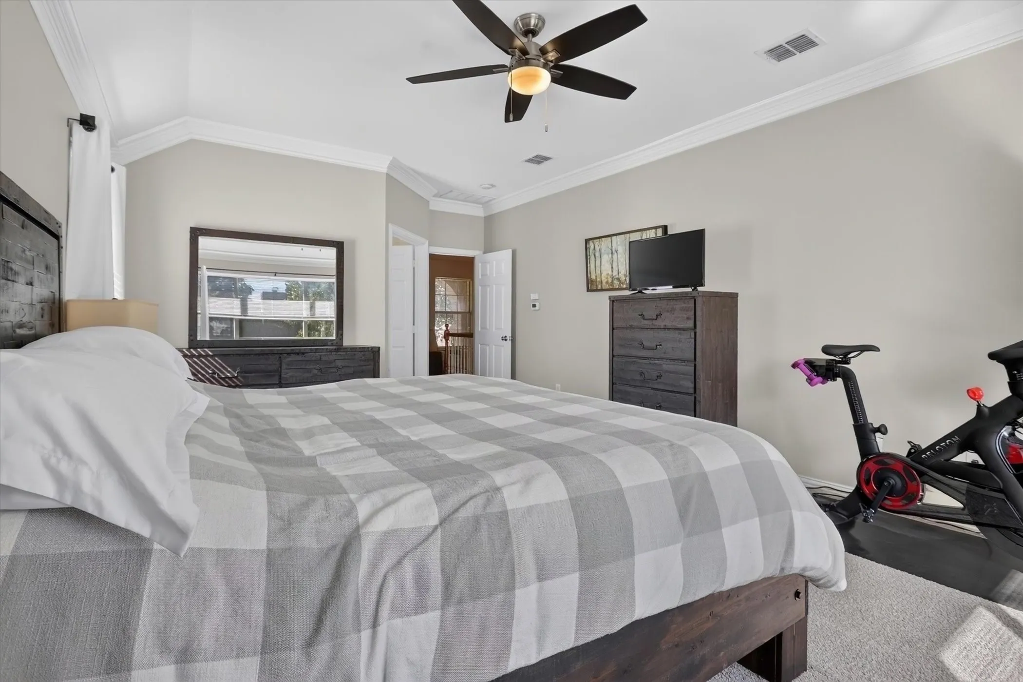 Tray ceiling featuring crown molding, neutral wall color, and a ceiling-mounted light and fan fixture