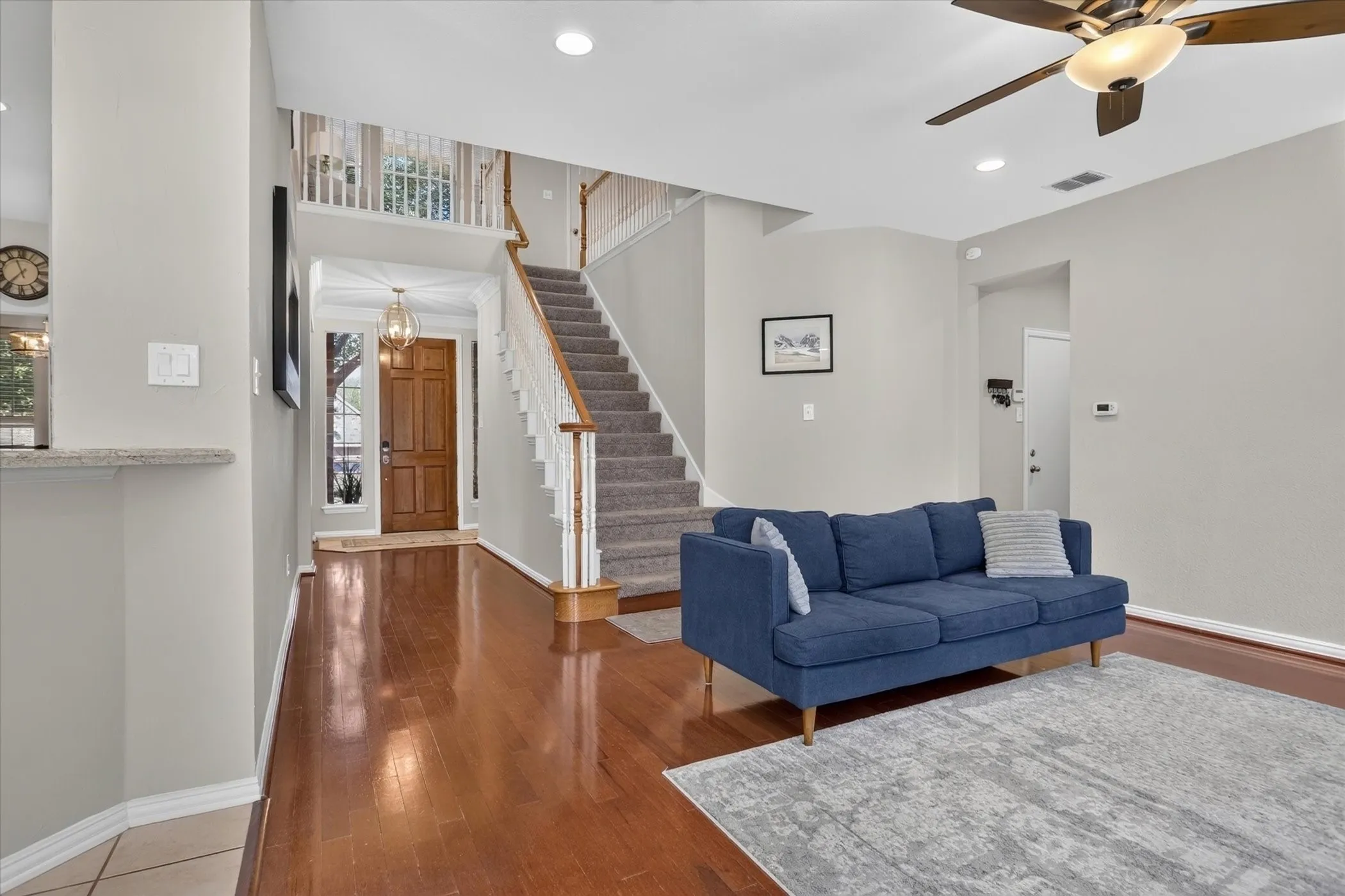 Entryway featuring wood-finish flooring, a carpeted staircase with white balusters, recessed lighting, and an attached ceiling fan