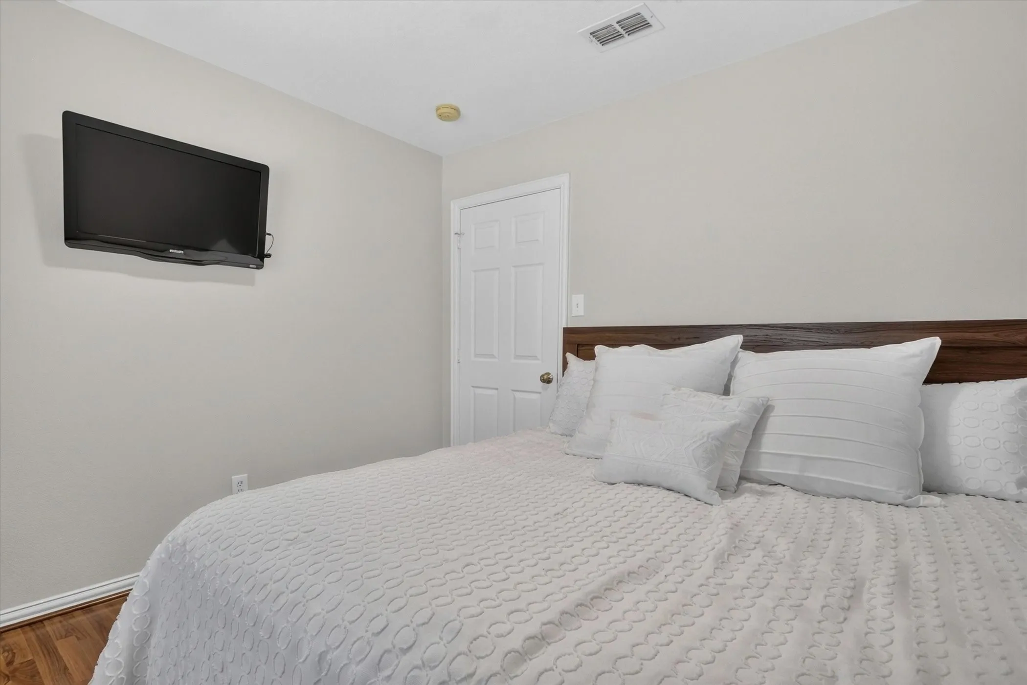 Wood-finish flooring, neutral wall paint, and a six-panel interior door
