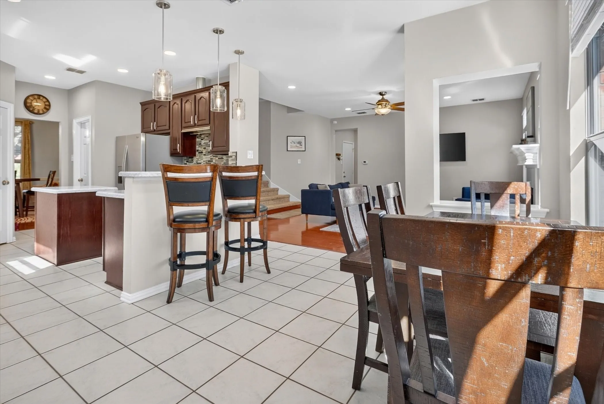 Kitchen featuring dark wood cabinetry, a breakfast bar with stone-look countertops, tiled flooring, and three glass pendant lights