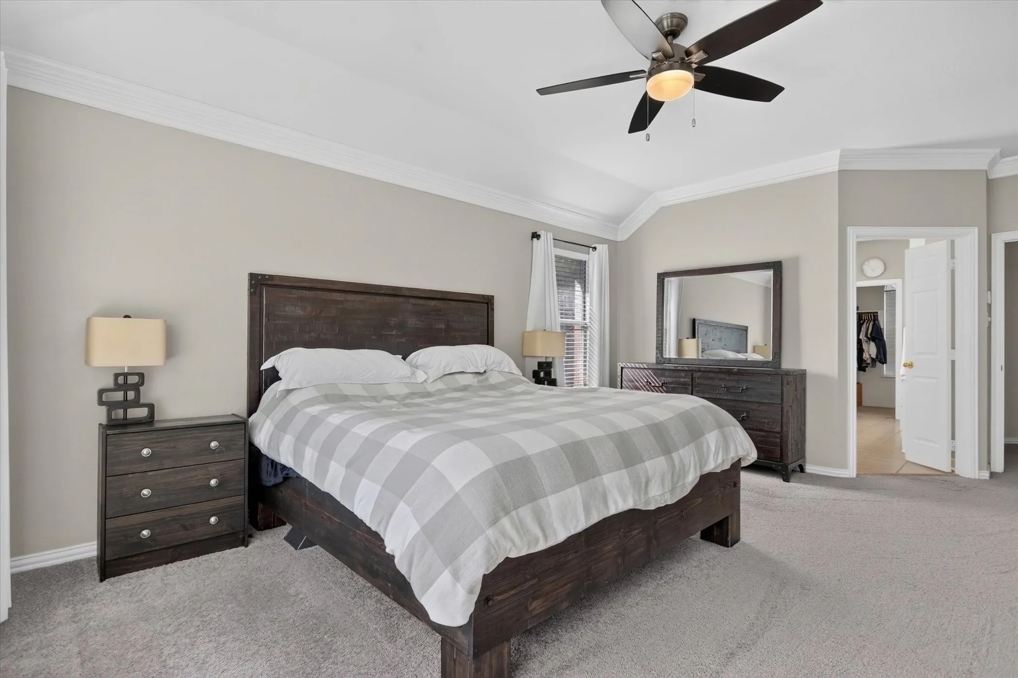Room featuring neutral wall paint, vaulted ceiling with crown molding, and a central ceiling fan with integrated lighting