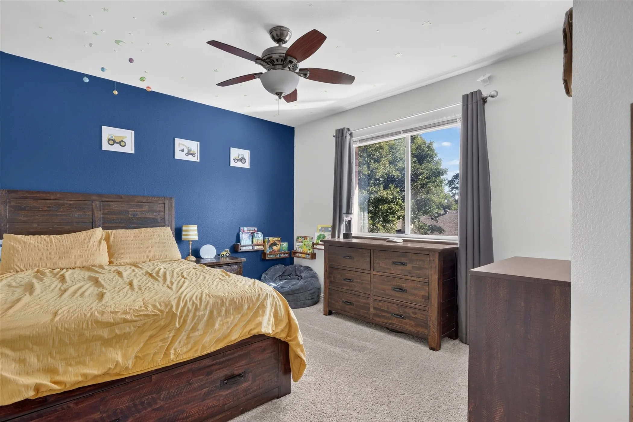 Bedroom featuring a ceiling-mounted fan with integrated lighting, wall-to-wall carpeting, and a dual-pane sliding window