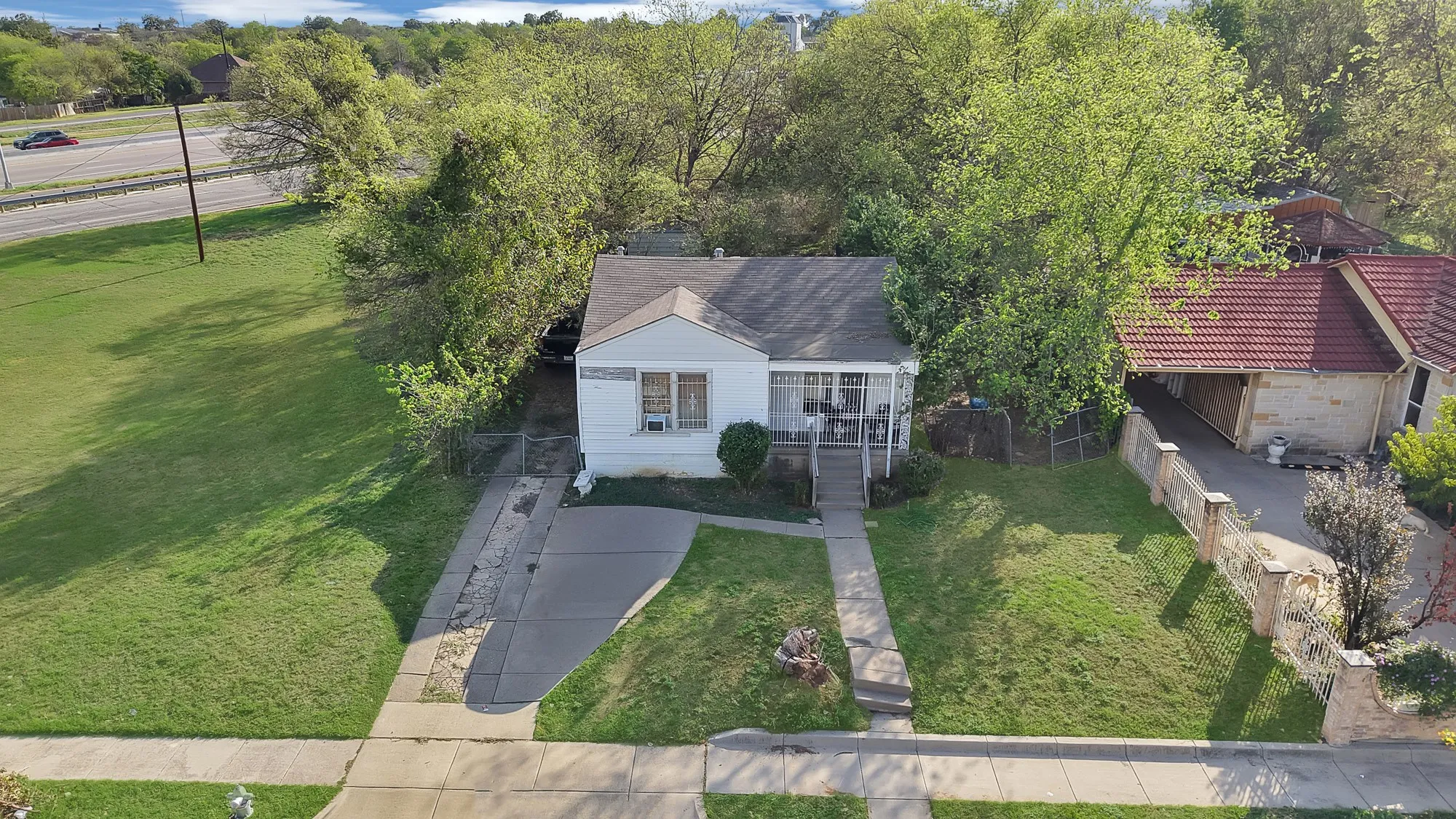 Single-story residence featuring a gabled roofline, concrete driveway, front porch with metal railing, and manicured lawn