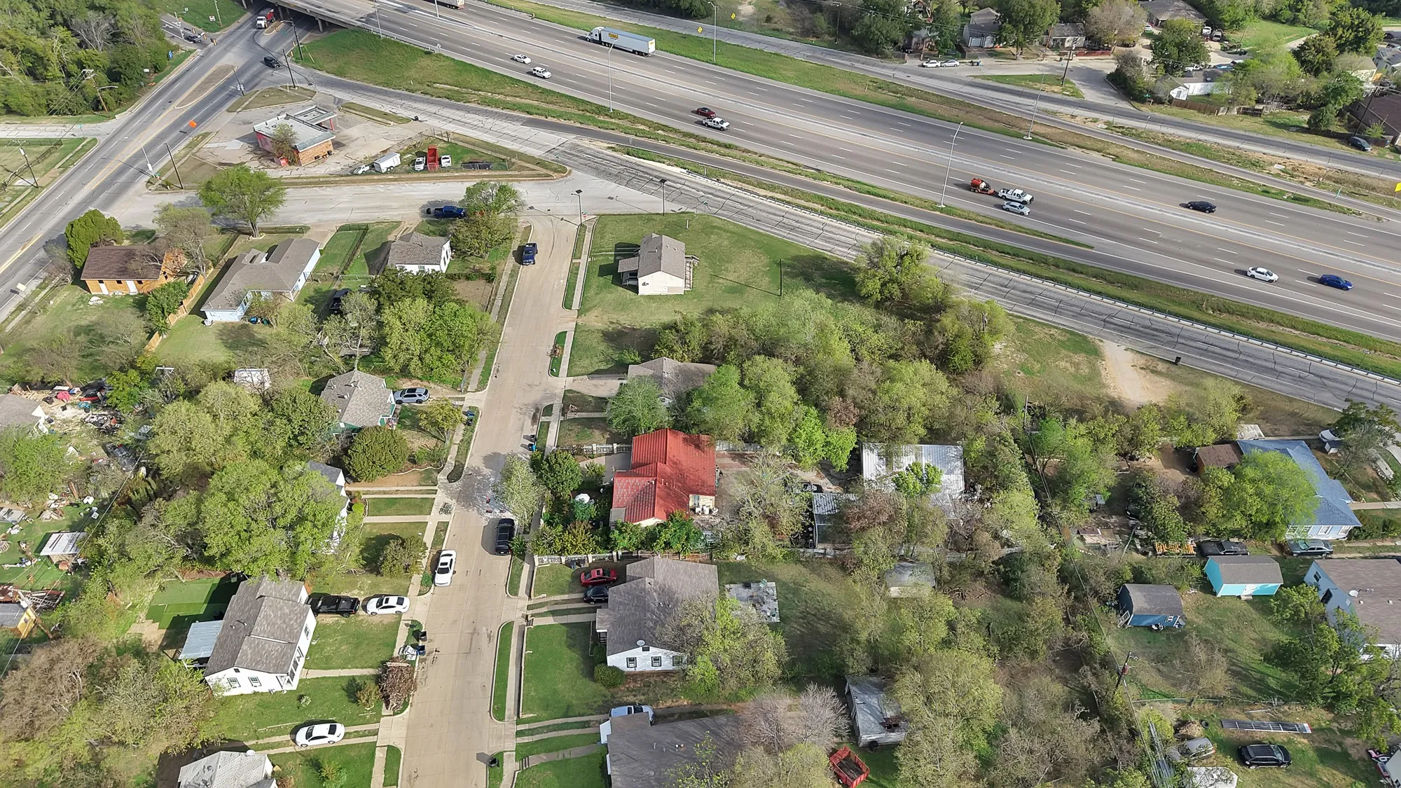 Aerial perspective of a residential corner lot featuring mature trees and established landscaping
