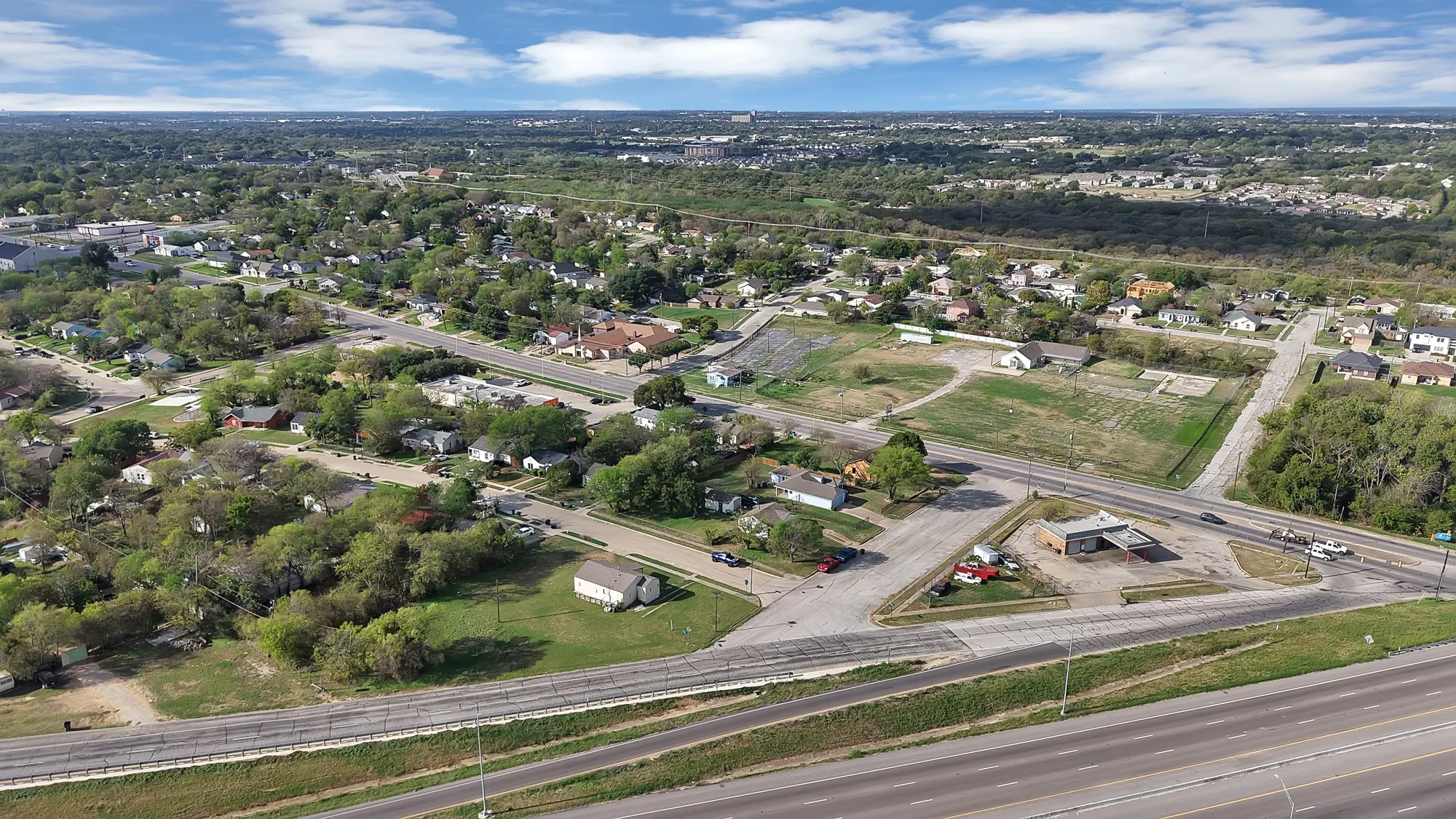 Aerial perspective showcasing a corner lot with frontage on multiple paved roads and direct proximity to a multi-lane highway