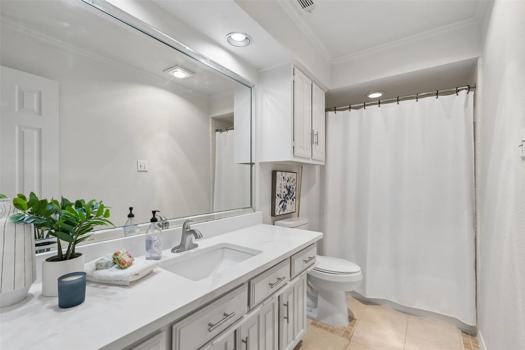 Bathroom featuring a vanity with a white countertop, an integrated rectangular sink, white cabinetry with brushed-metal pulls, a full-width wall mirror, and a tub-shower combination