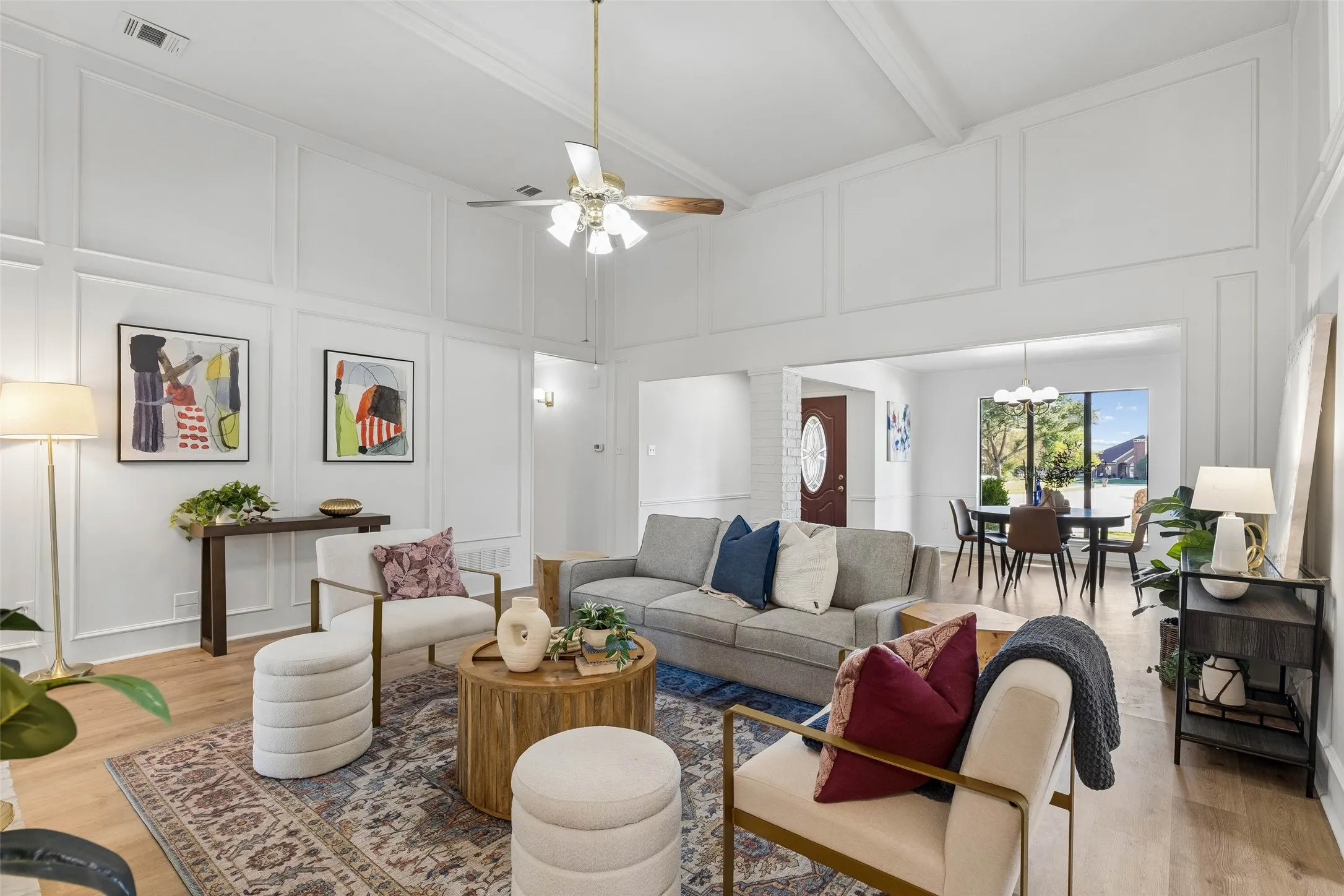 High-ceilinged room featuring extensive wall paneling, wood-finish flooring, and a central ceiling fan