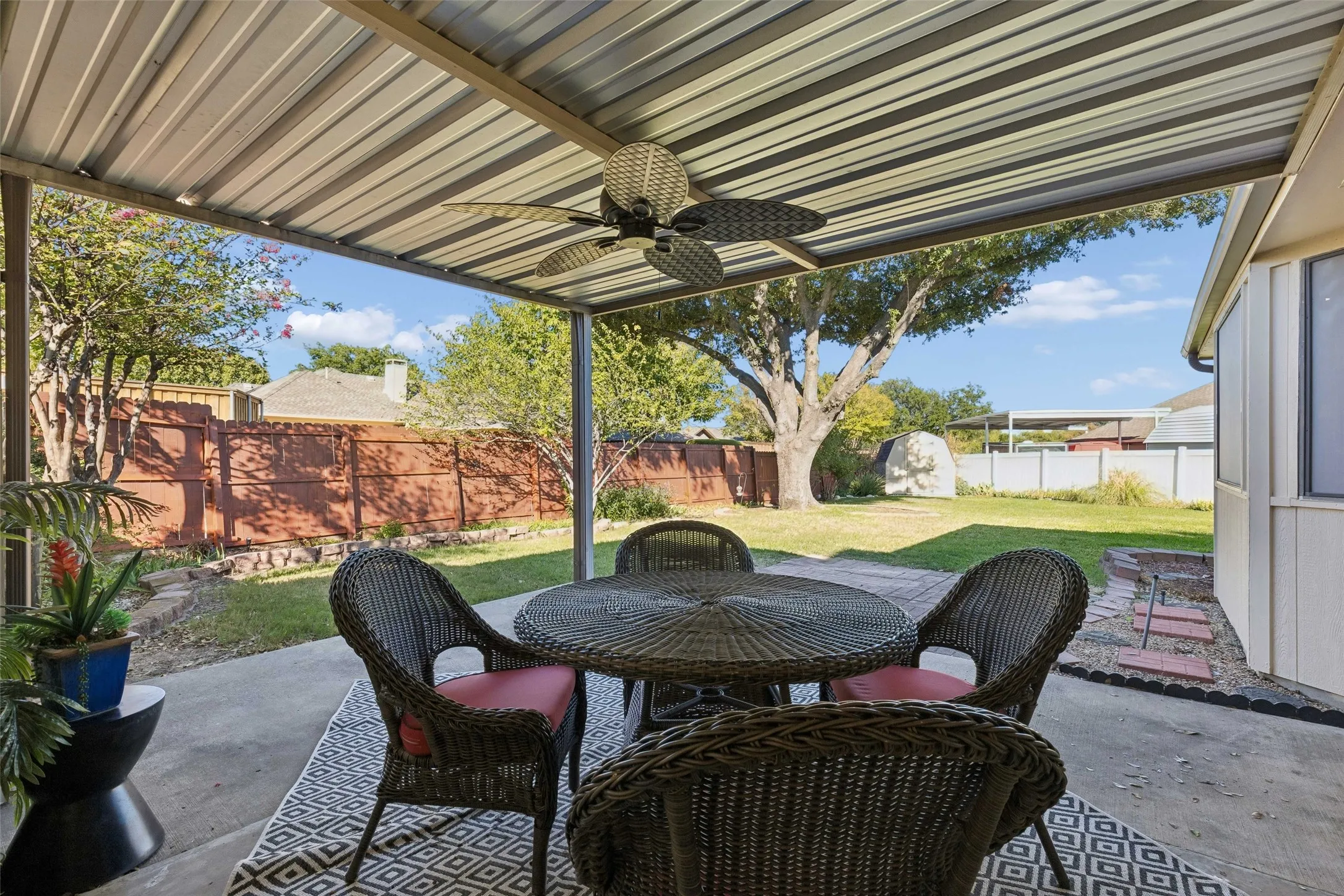 Covered patio featuring a corrugated metal roof, integrated ceiling fan, concrete flooring, and backyard access