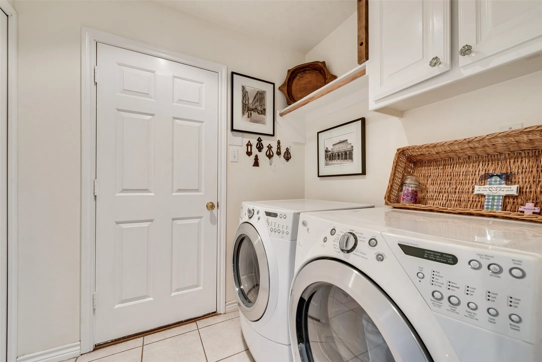 Utility area featuring white shaker-style wall cabinets, a natural wood floating shelf, and neutral tile flooring
