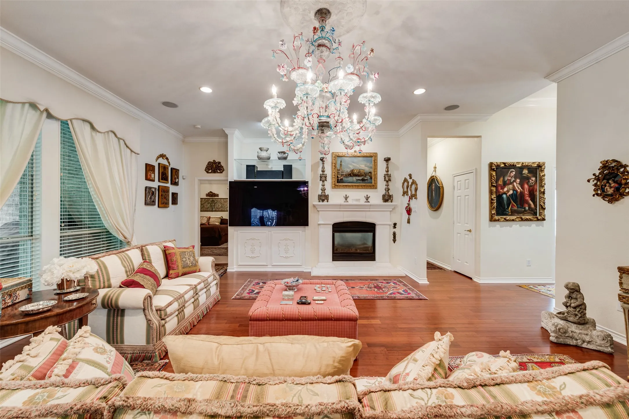 Living area featuring wood-finish flooring, a fireplace with a white mantel, built-in cabinetry, recessed lighting.
