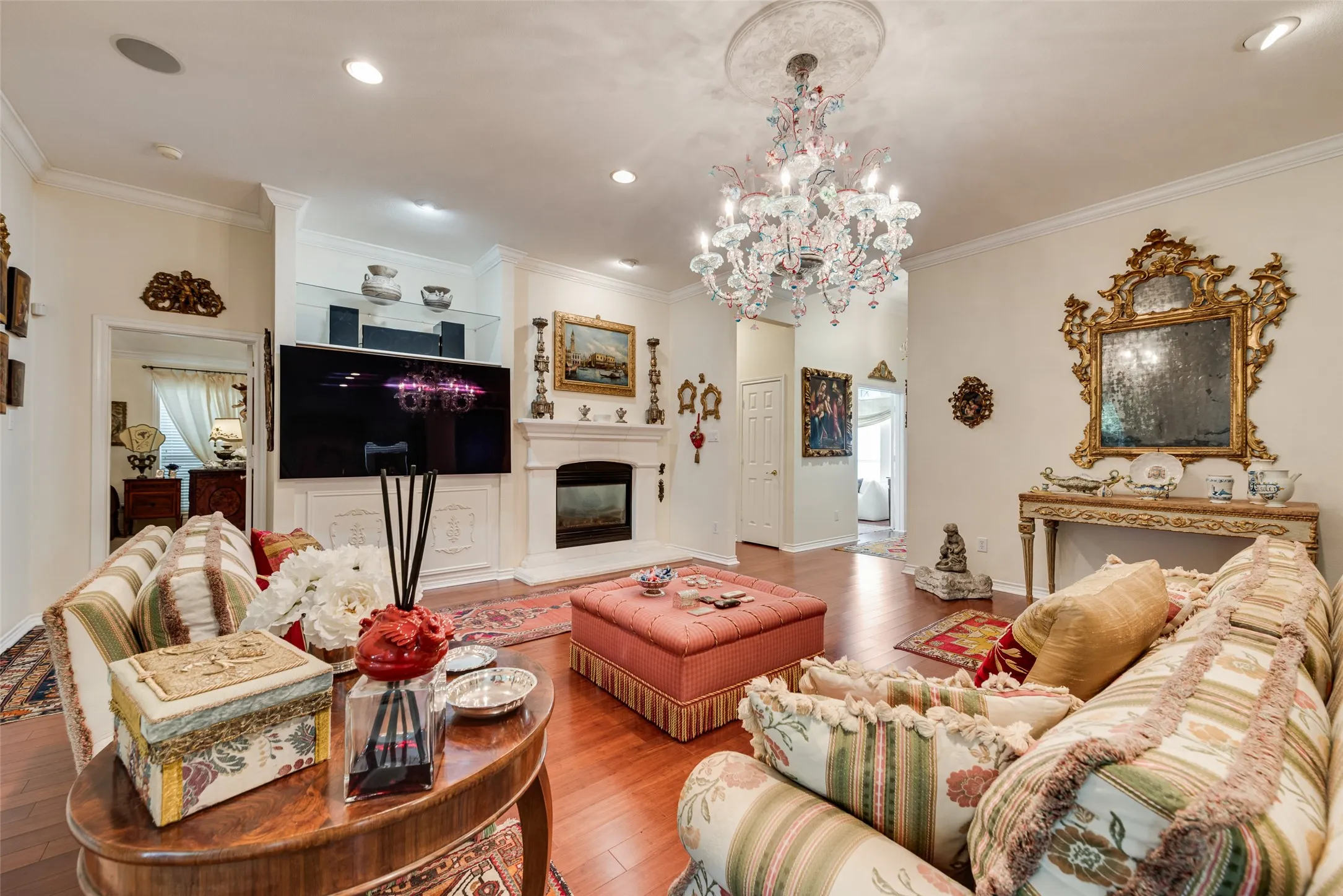 Living room featuring wood-finish flooring, a decorative fireplace with a mantle, recessed lighting, and a crystal chandelier with a ceiling medallion