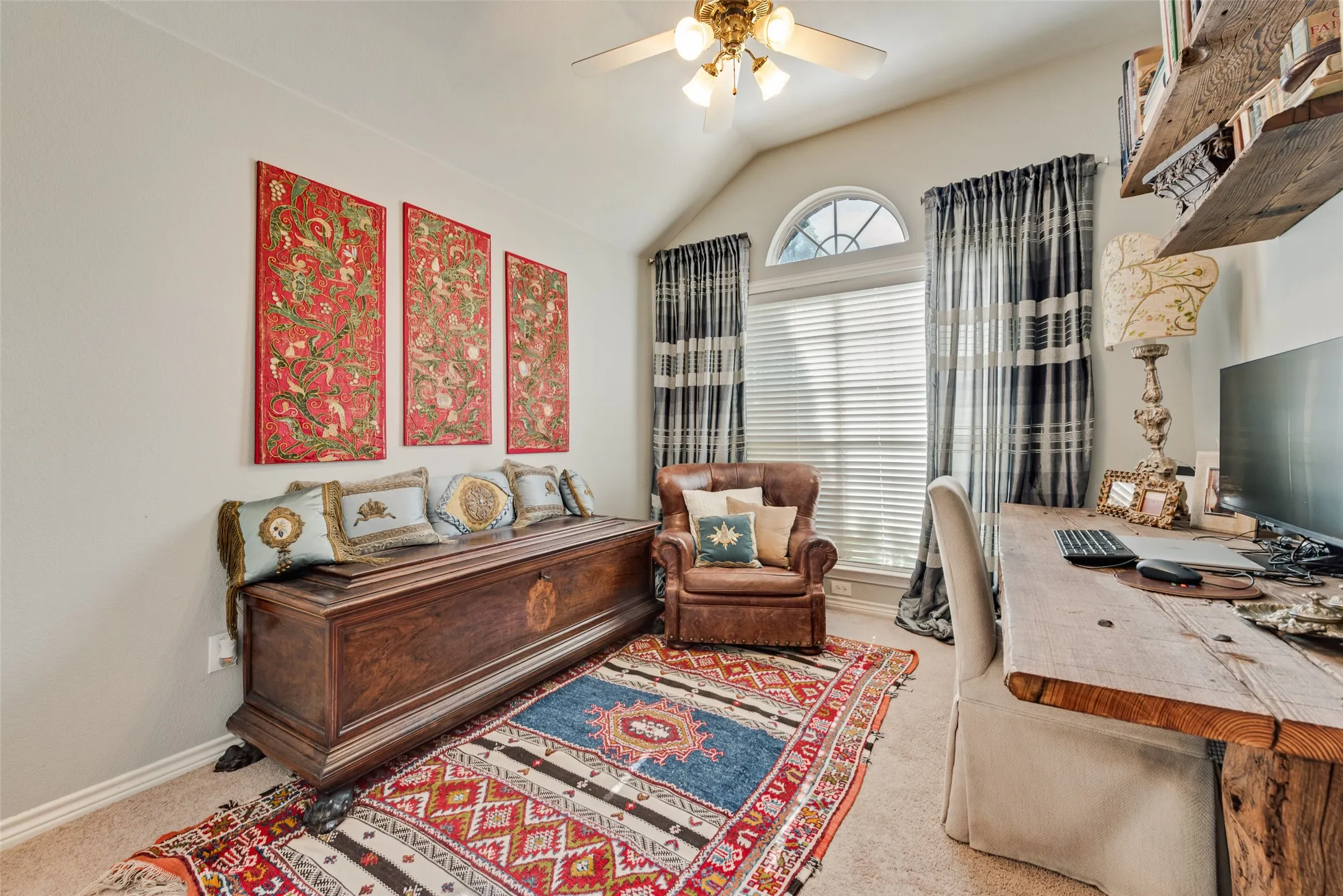 Vaulted ceiling with an integrated light fixture and ceiling fan, arched window, and wall-mounted shelving