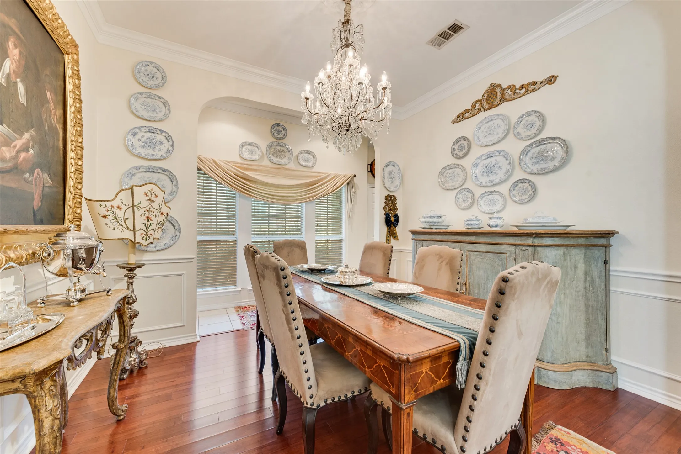 Formal dining area featuring wood-finish flooring, wainscoting, crown molding.