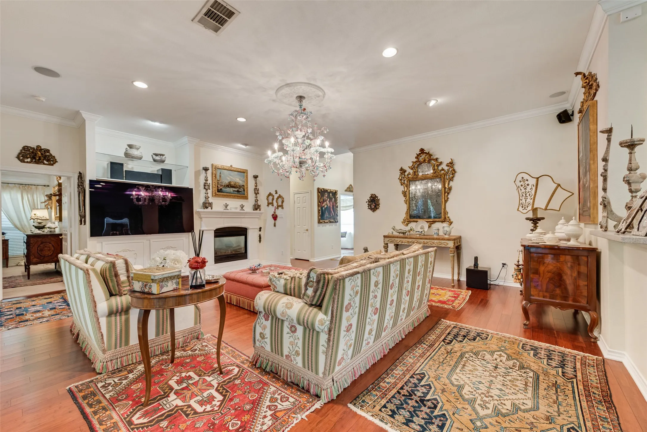 Living room featuring wood-finish flooring, a fireplace with a decorative mantel, recessed lighting, and built-in cabinetry