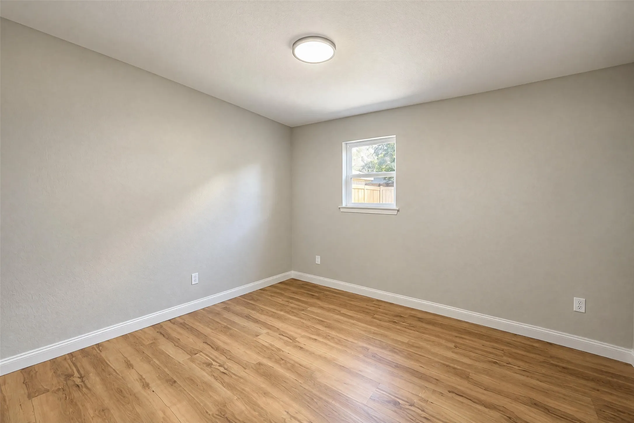Neutral-toned interior walls, wood-finish flooring, and a flush-mount overhead light fixture