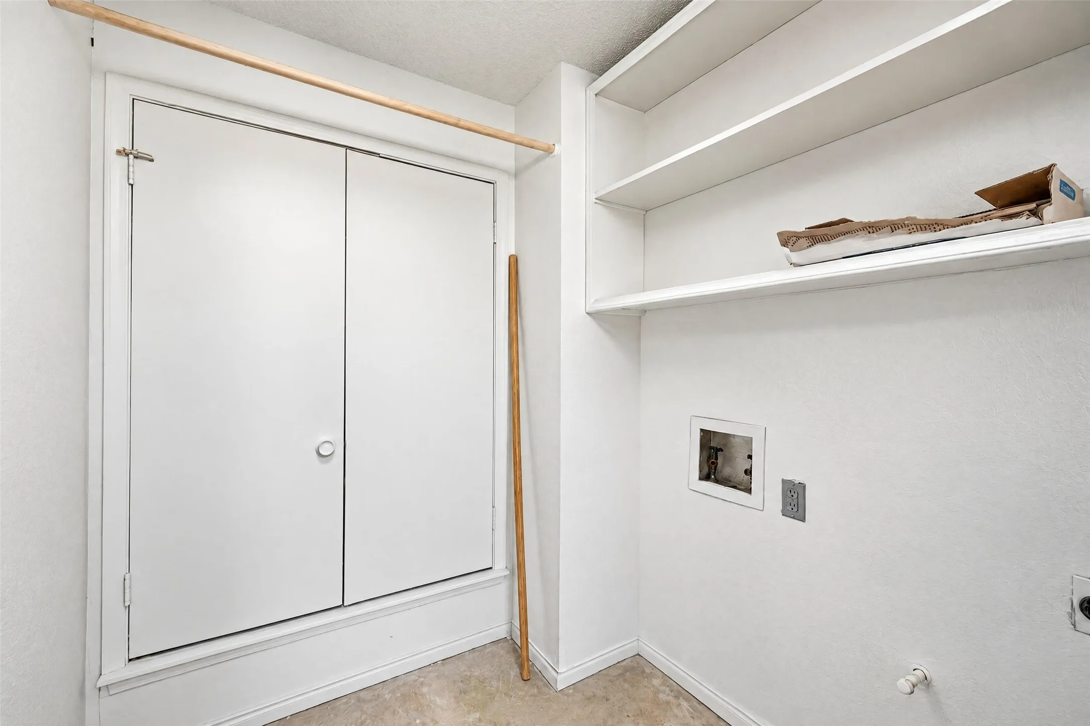 Laundry utility area featuring dual-panel closet doors, white built-in shelving, and dedicated water and electrical hookups