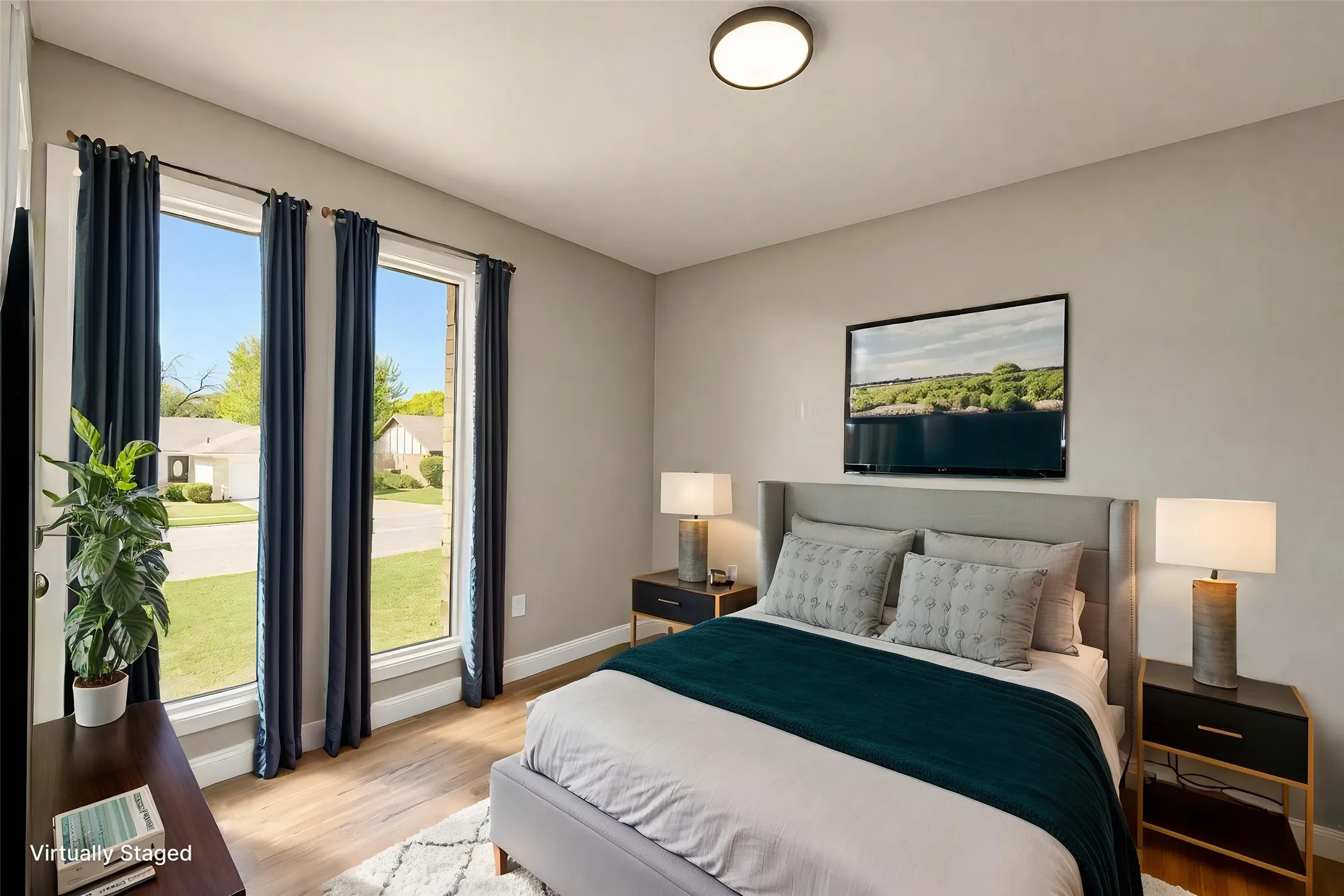 Dual full-height windows, wood-finish flooring, and a central ceiling-mounted light fixture