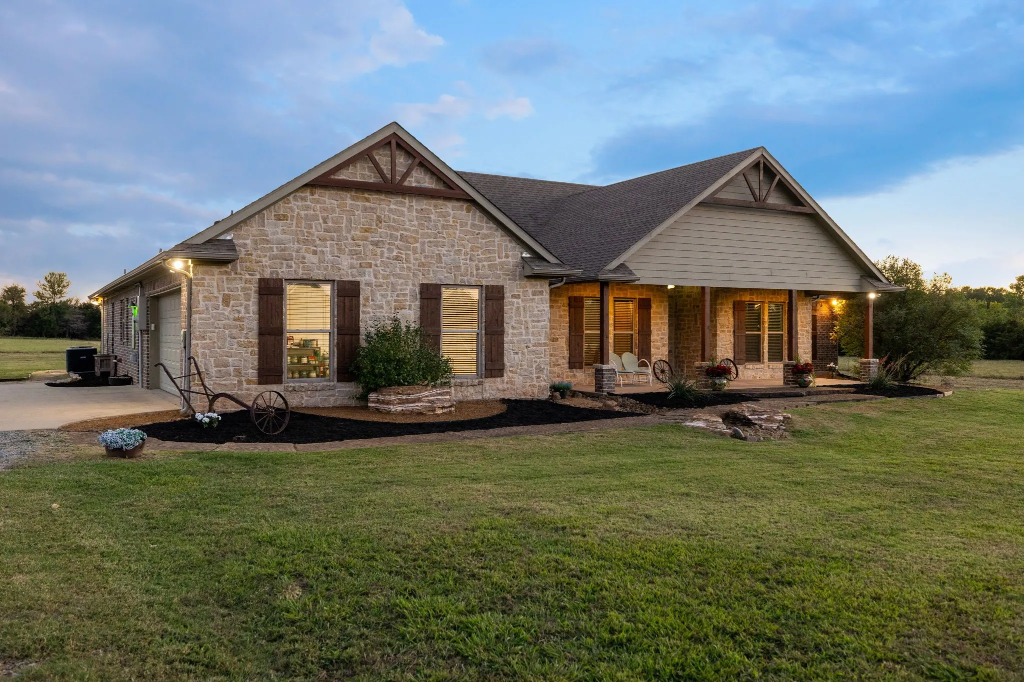 Stone and horizontal siding exterior featuring dual gabled rooflines, decorative timber truss accents, dark-toned shutters, and a covered front porch