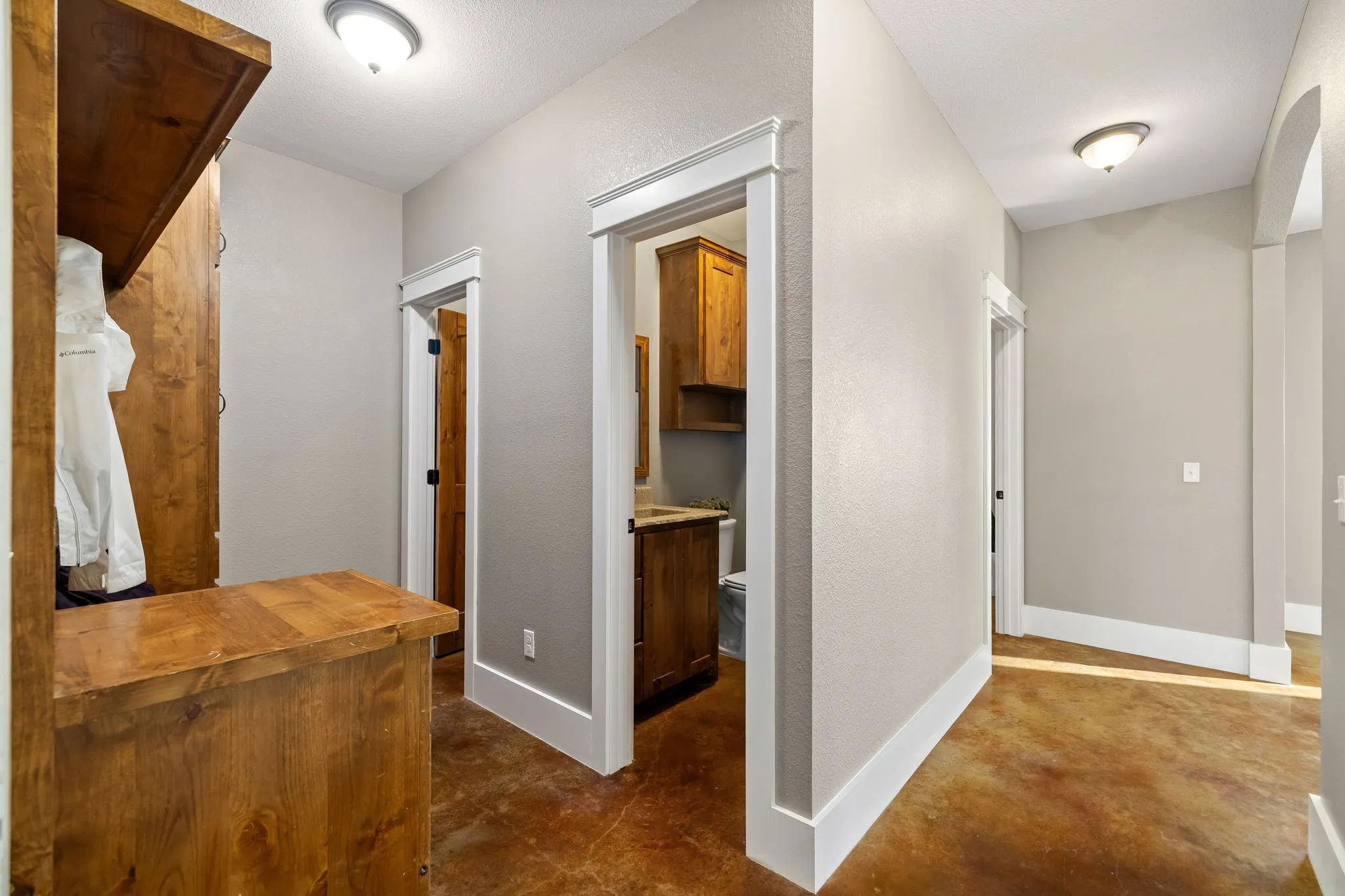 Hallway featuring stained concrete flooring, custom wood-finish built-in cabinetry, and archway architectural detailing