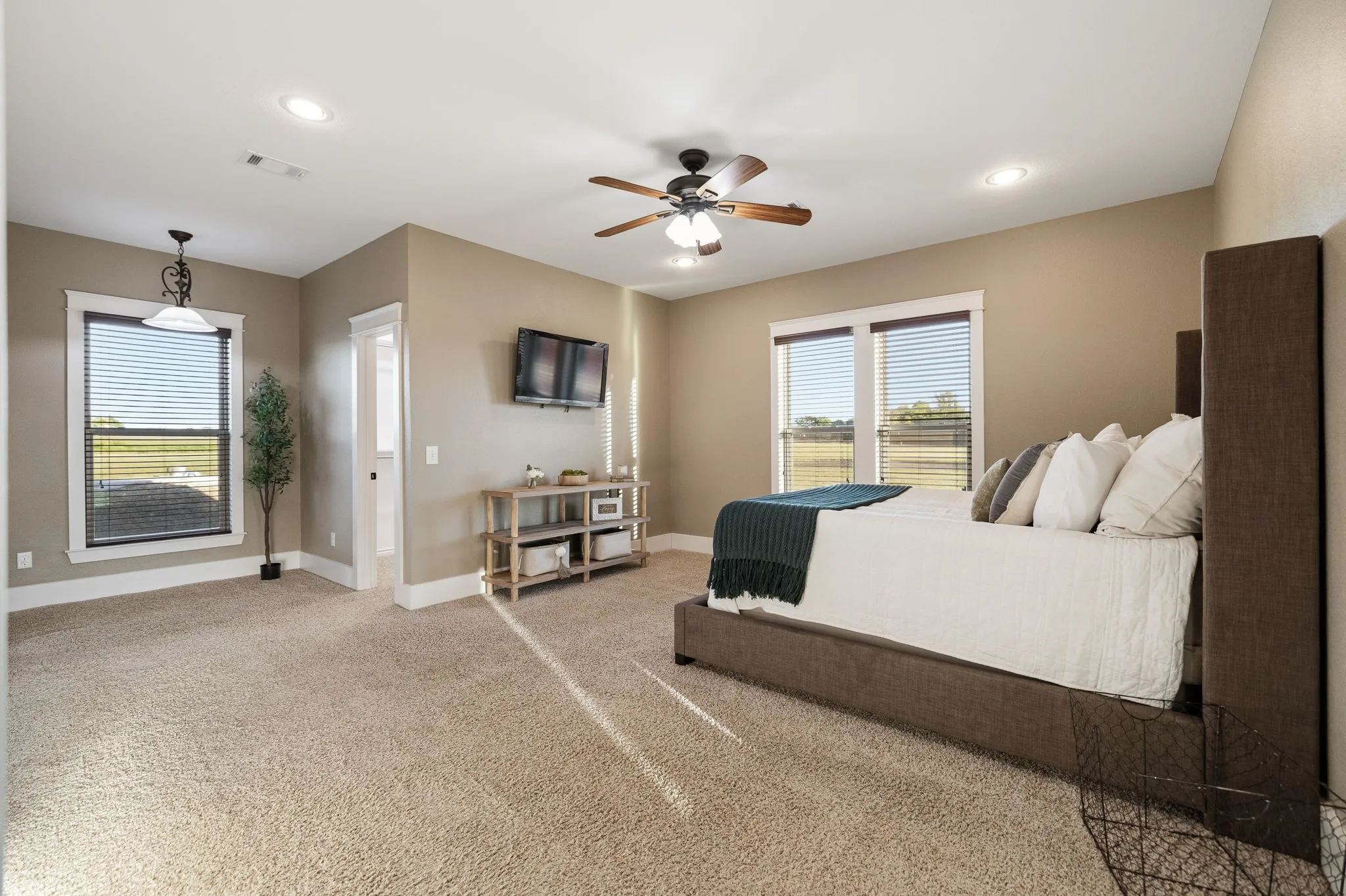 Spacious room featuring neutral carpeting, recessed lighting, a ceiling fan, and large windows with integrated blinds