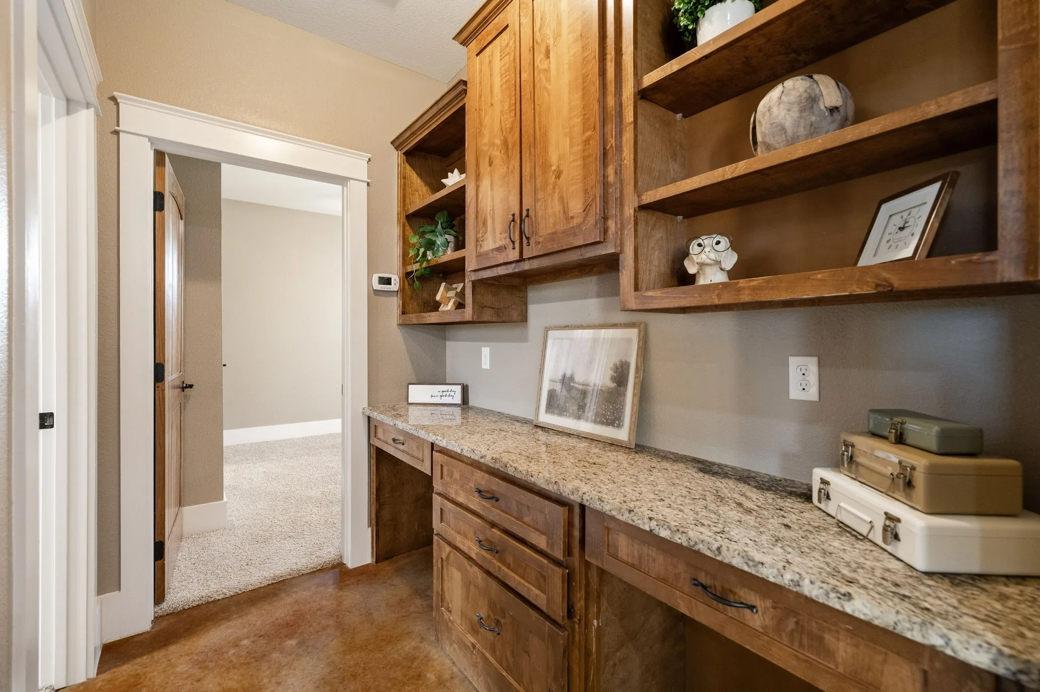 Built-in wood cabinetry, integrated shelving, stone-finish countertops, drawer storage, and polished concrete flooring