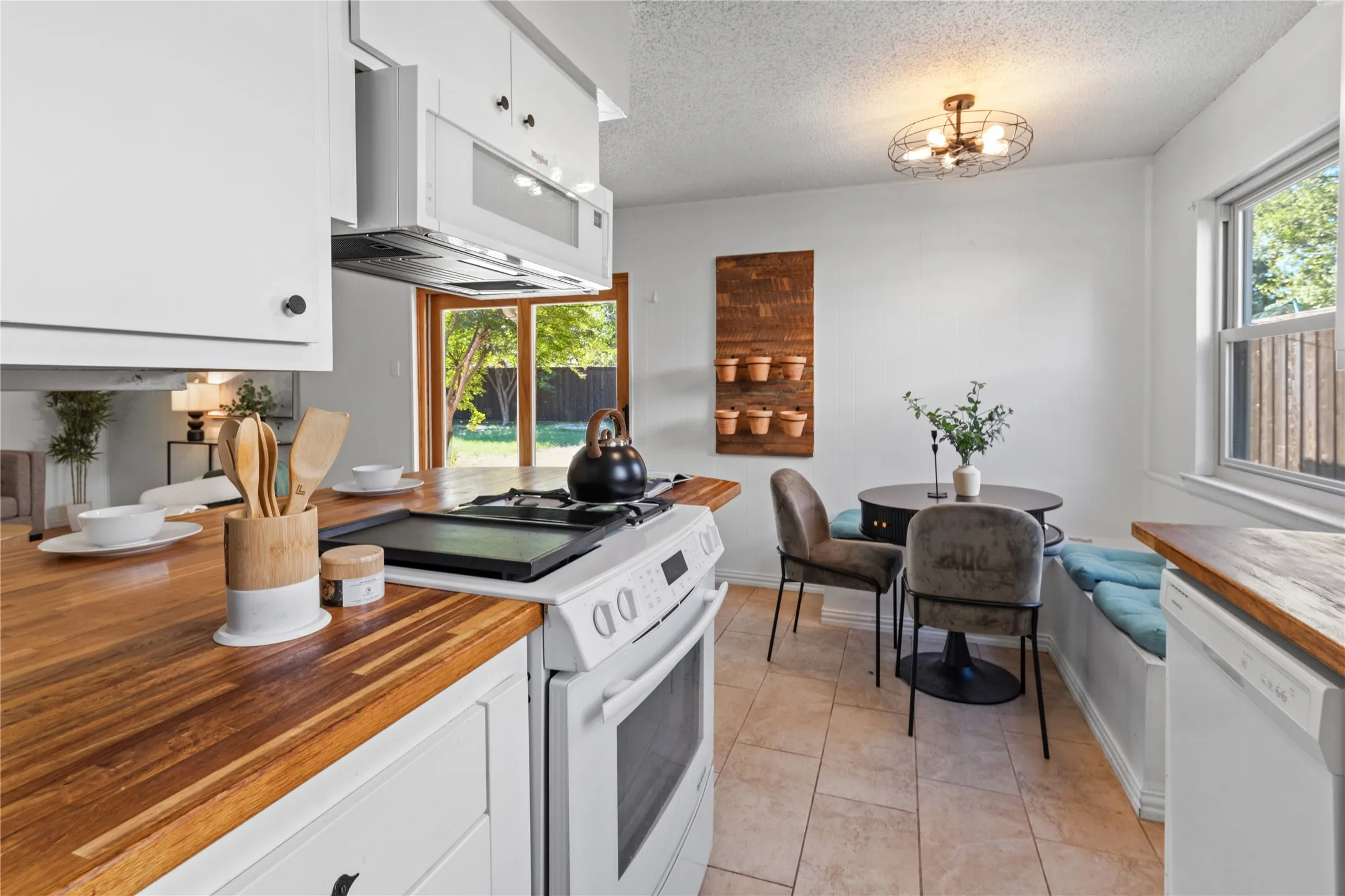 Kitchen featuring wood-finish countertops, white cabinetry, a built-in microwave, tile flooring, and a sliding glass door