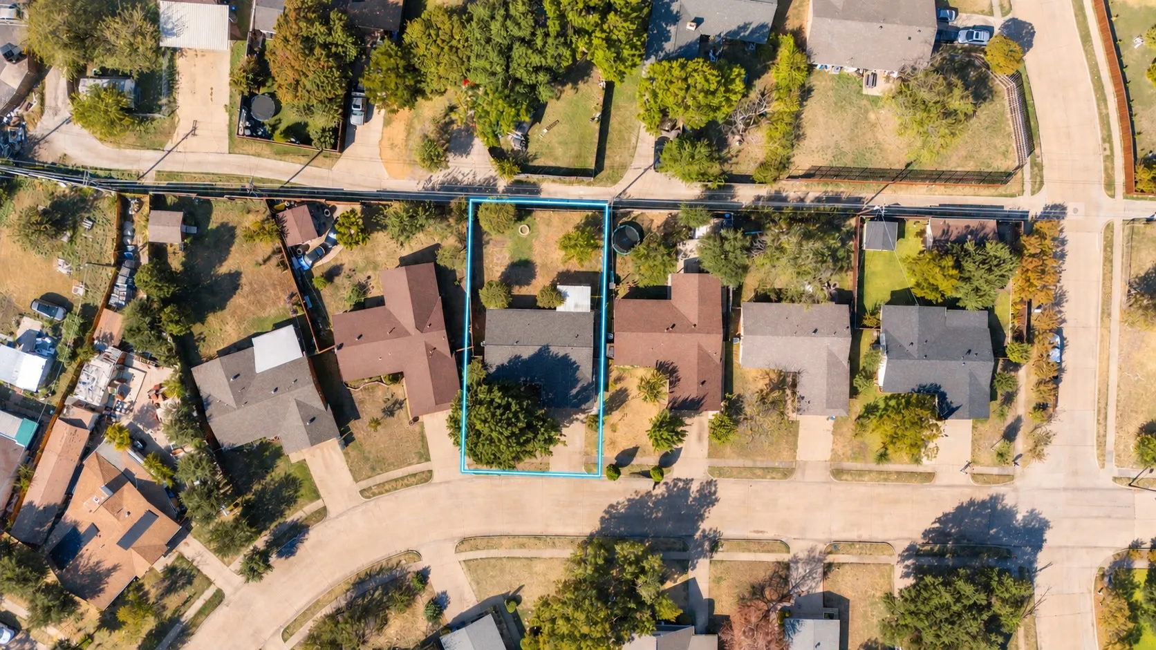 Aerial perspective of a residential property featuring an expansive backyard, mature landscaping, and a rectangular lot configuration