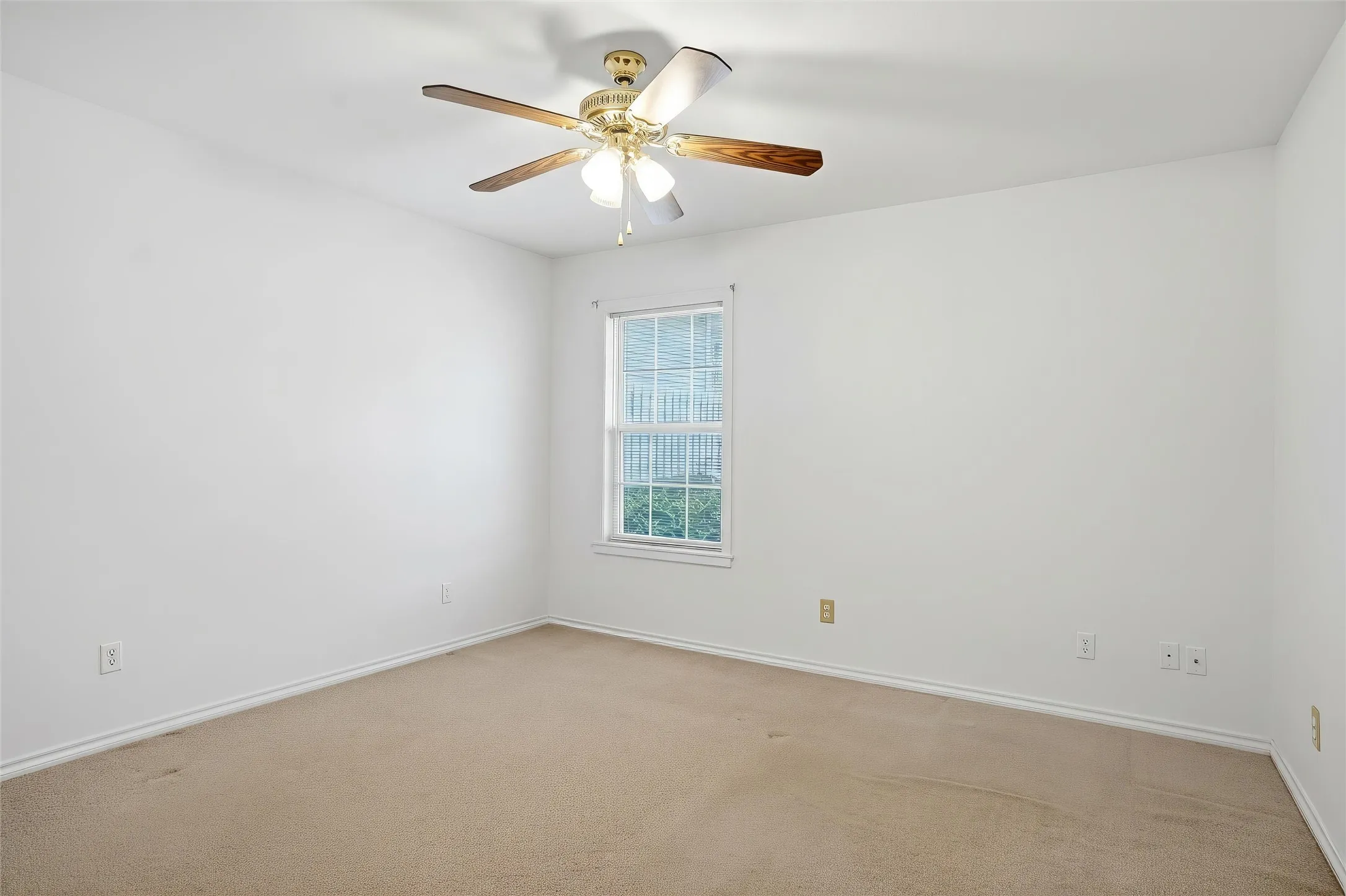 Light-toned carpeting and white walls with a single window featuring blinds and a ceiling fan