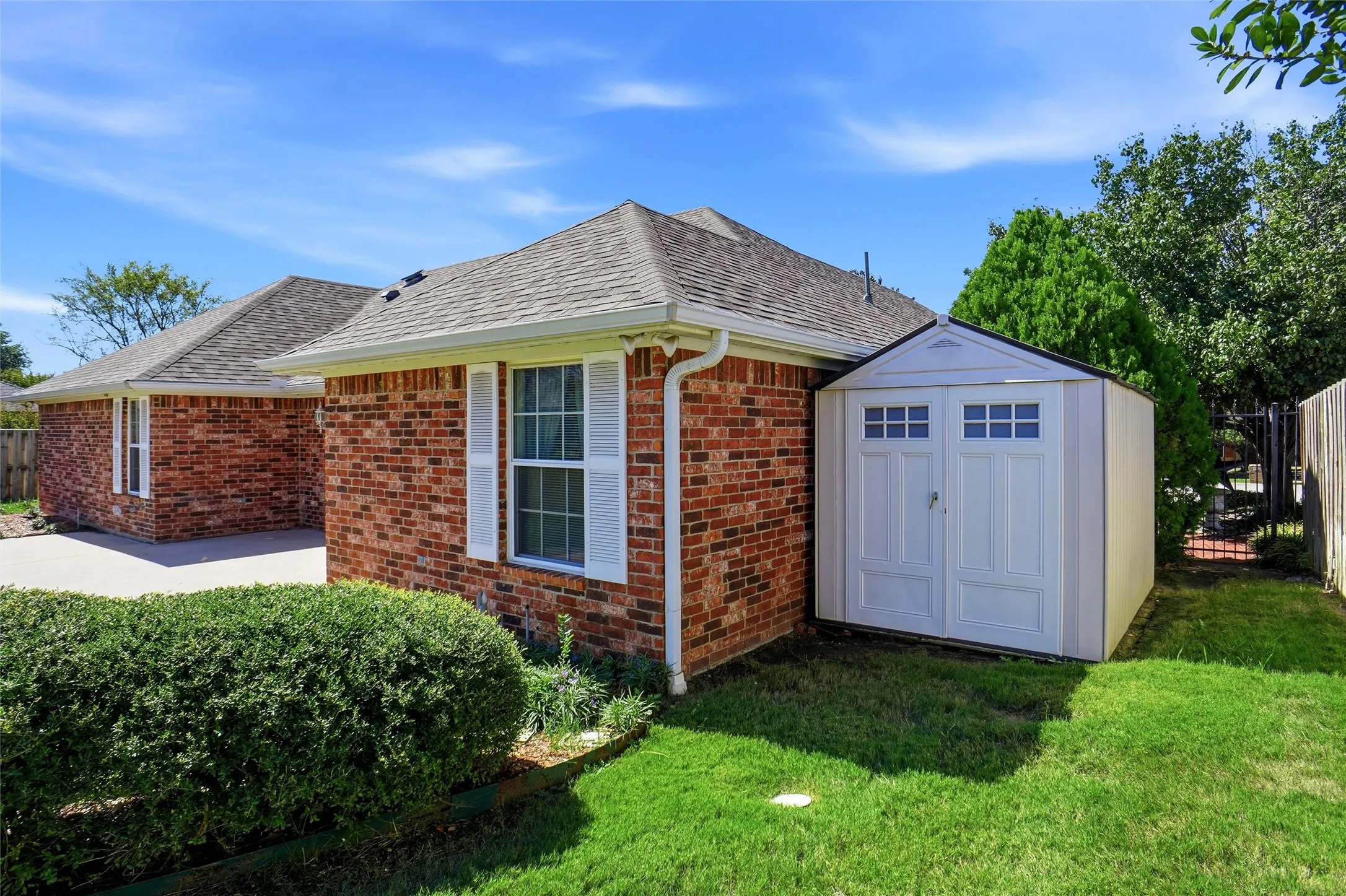 Brick exterior with white shutters, an asphalt shingle roof, and white rain gutters.  Notice the storage room next to the house which will stay with the property.