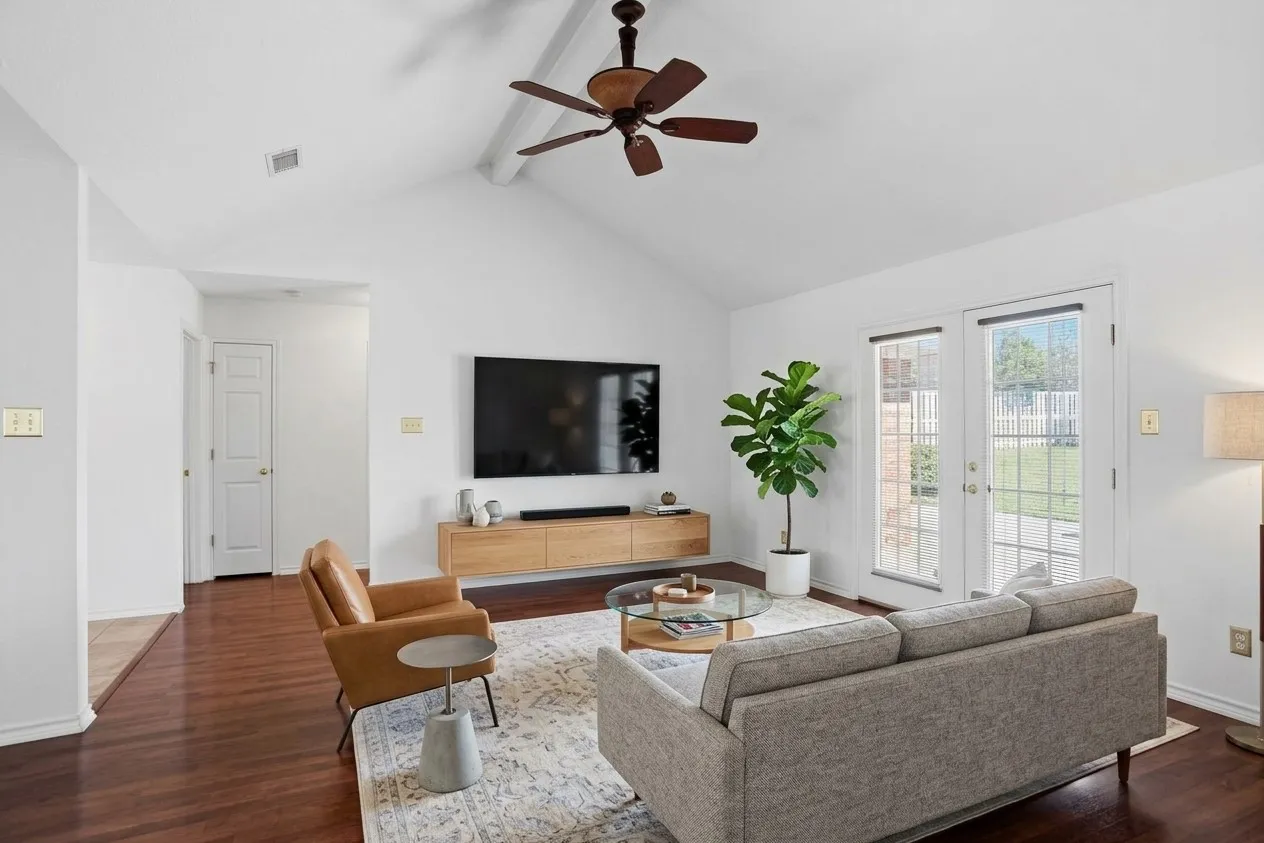 AI enhanced photo. Vaulted ceiling with a ceiling fan, laminate flooring, white walls, and glass-paneled double doors