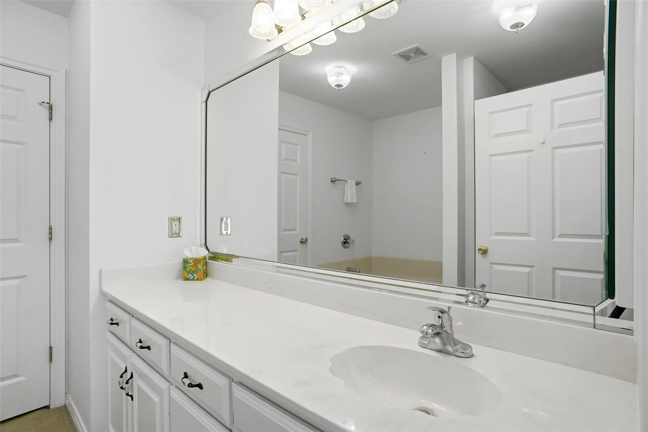 White vanity with black hardware, integrated sink, and chrome faucet.