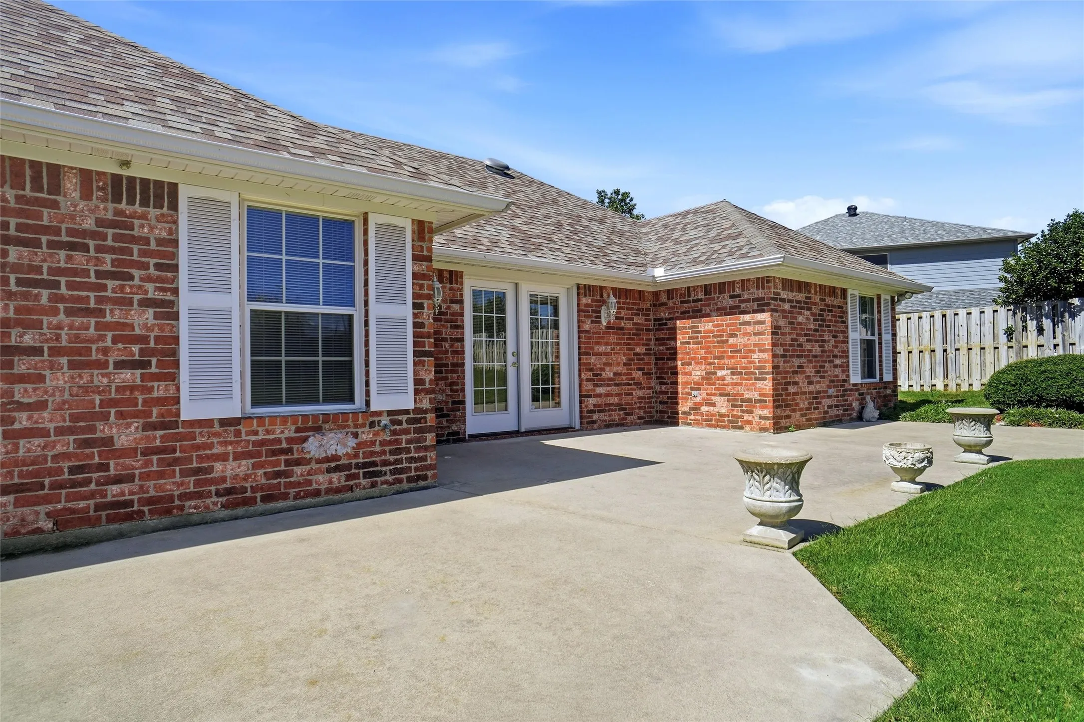 Brick exterior with white window shutters and extended concrete patio