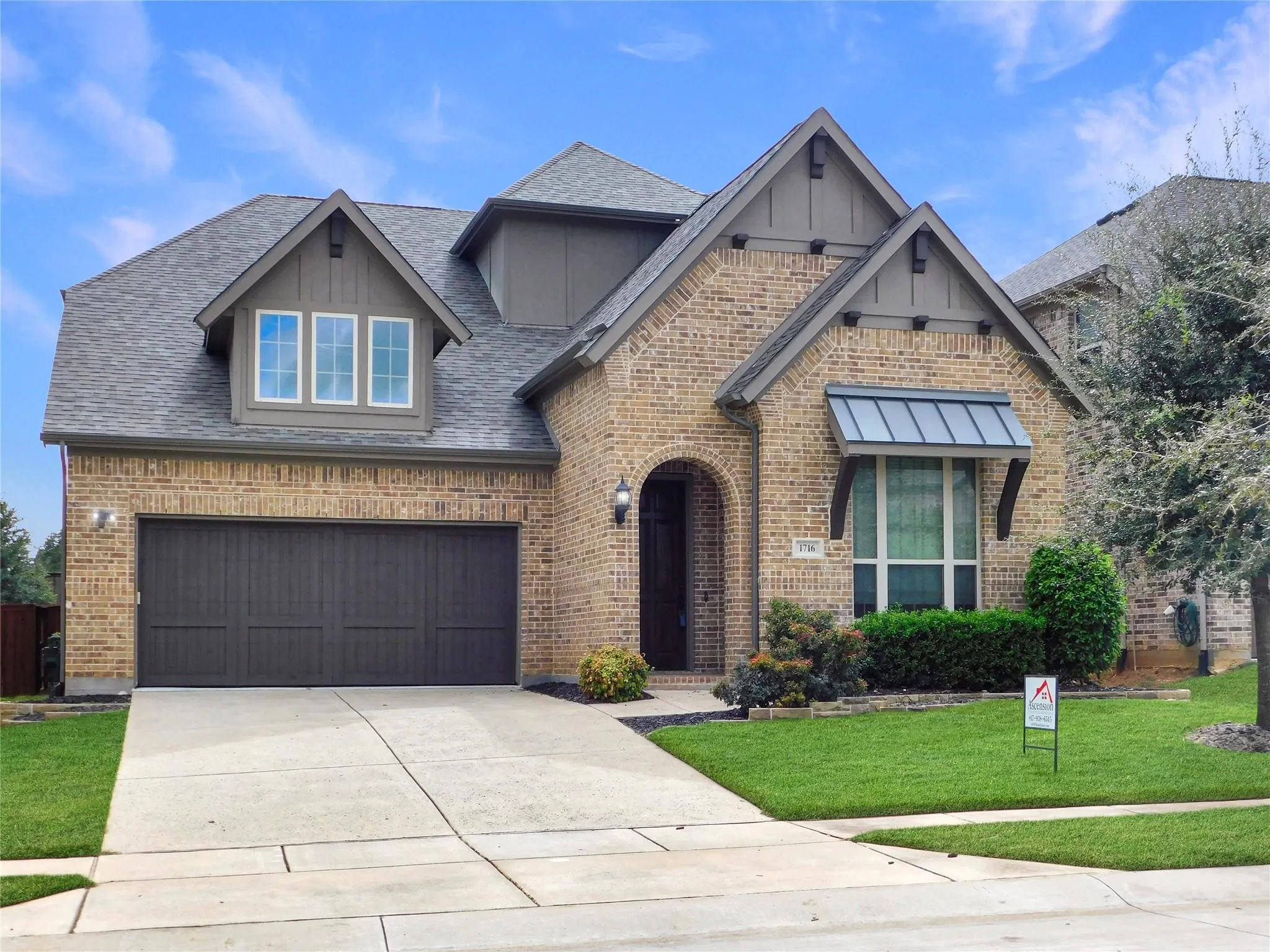Multi-gabled brick exterior featuring decorative timber accents, a dual-car garage, and a metal-awning window detail