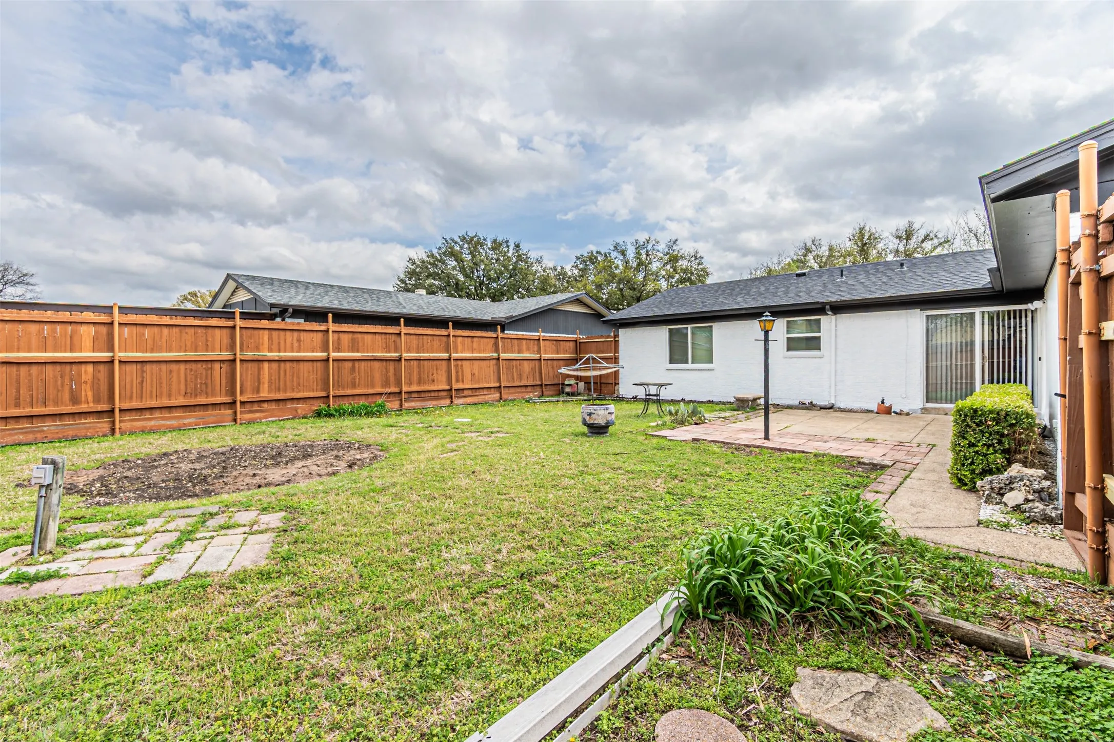 Backyard featuring a privacy wood fence, concrete patio, and sodded lawn
