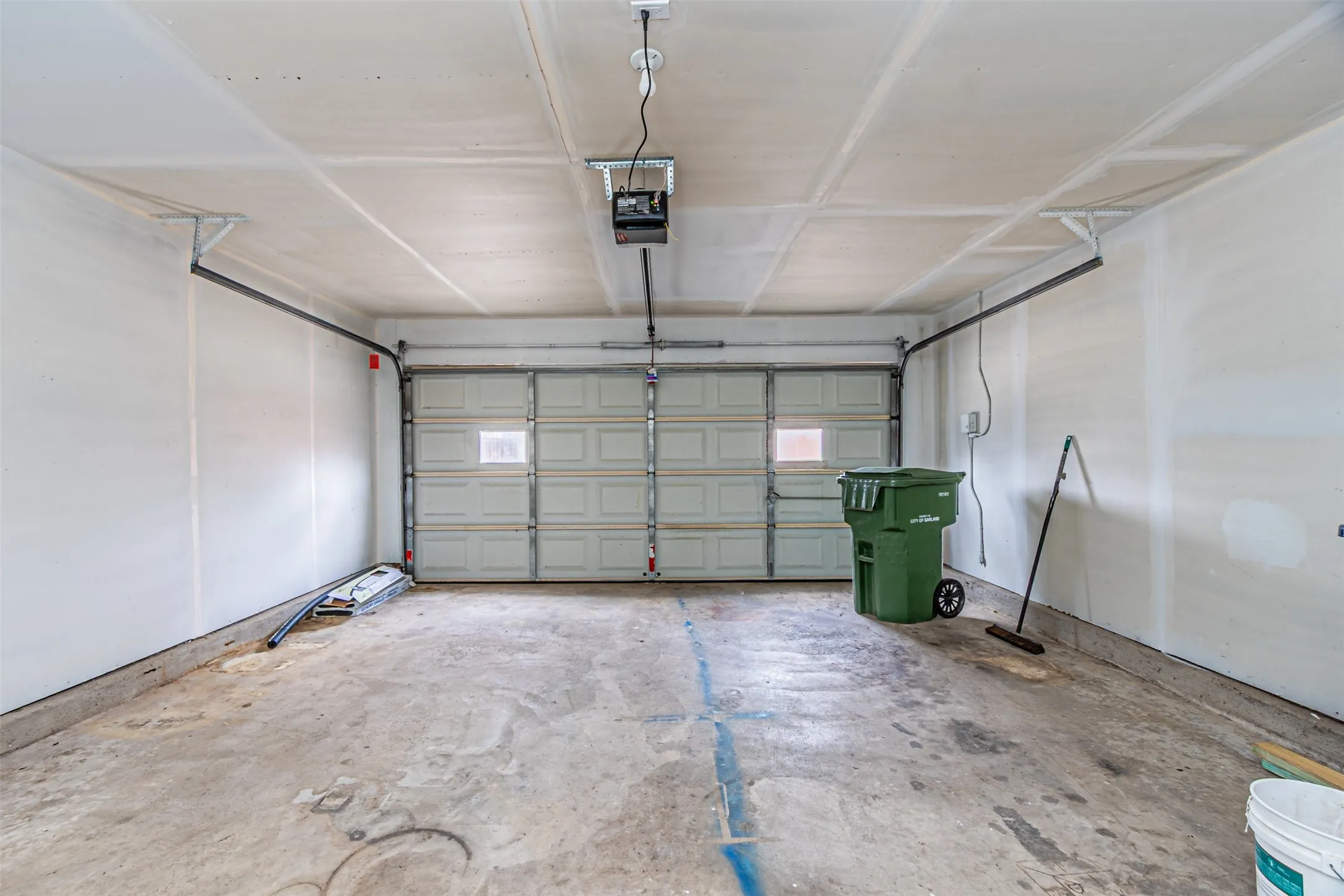 Two-car garage featuring a sectional metal door with inset windows, concrete flooring, and an automated overhead door opener