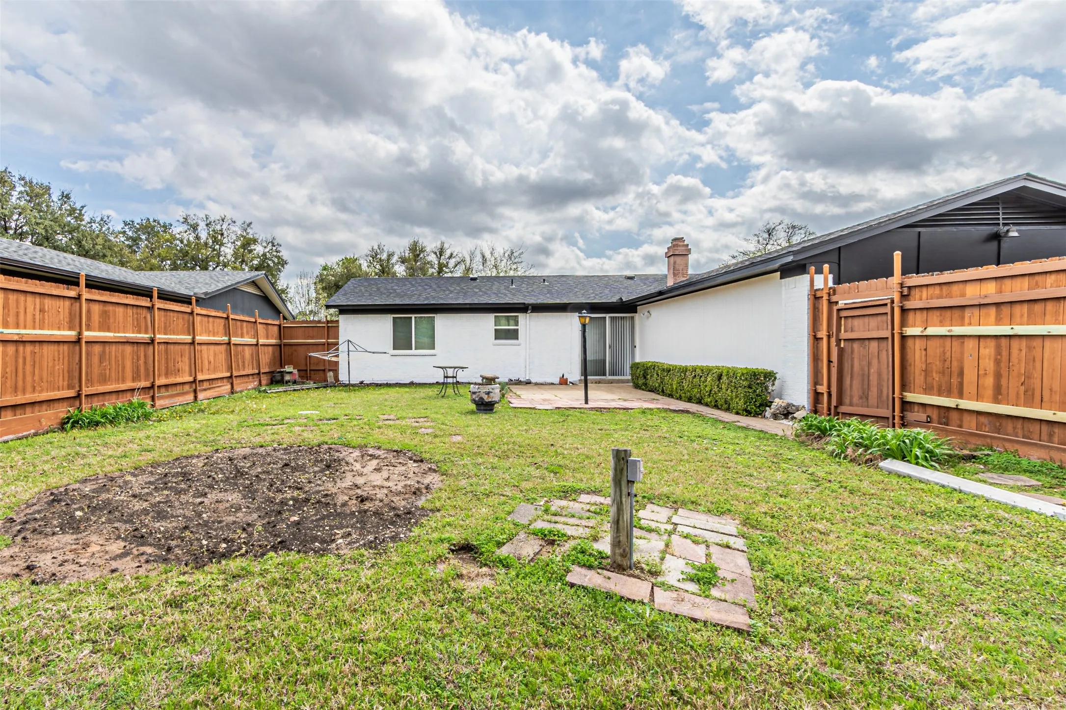 Backyard featuring a privacy wood fence, stone patio, and exterior brick finish