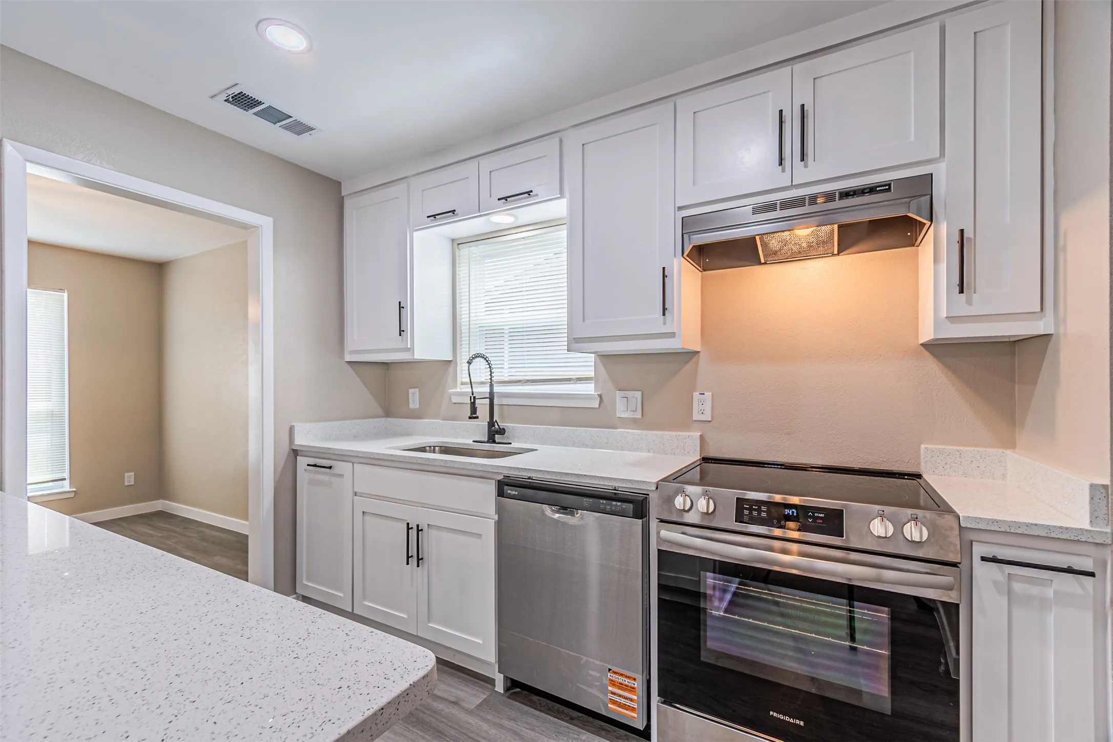 Kitchen featuring white shaker-style cabinetry, quartz countertops, stainless steel appliances, and a matte black gooseneck faucet