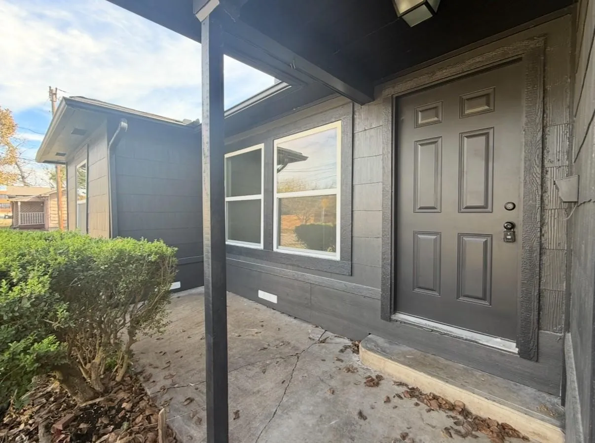 Covered porch entry featuring dark exterior siding, six-panel door, and dual-pane windows