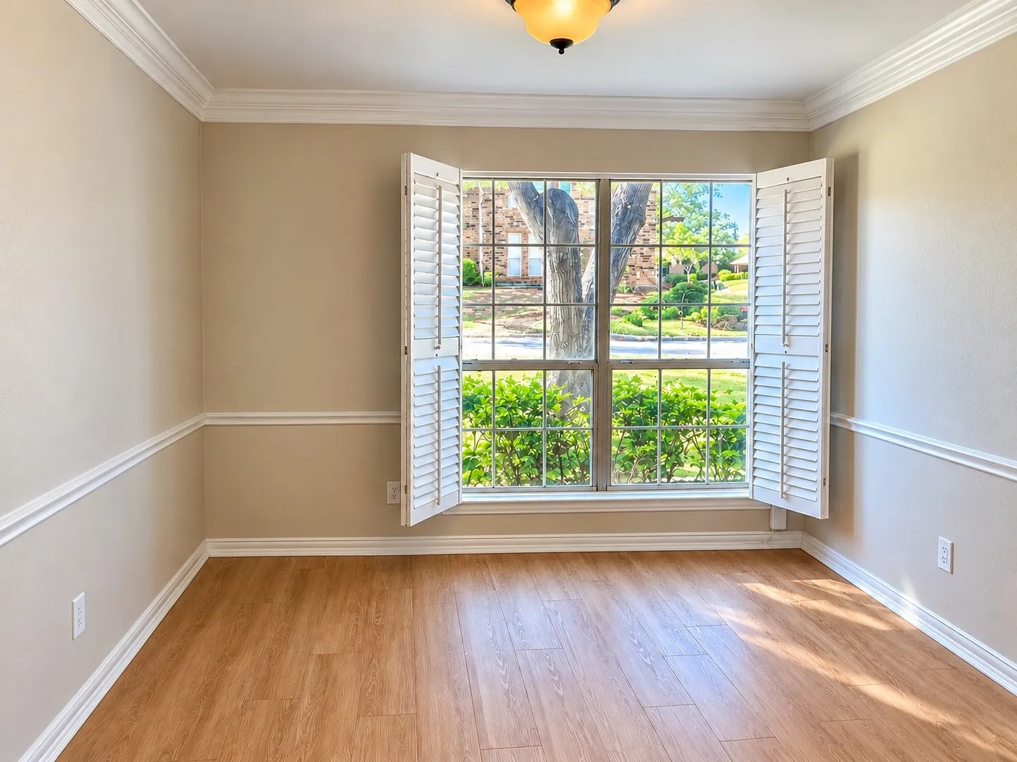 Wood-finish flooring, white plantation shutters, crown molding, chair rail trim, and a ceiling-mounted light fixture