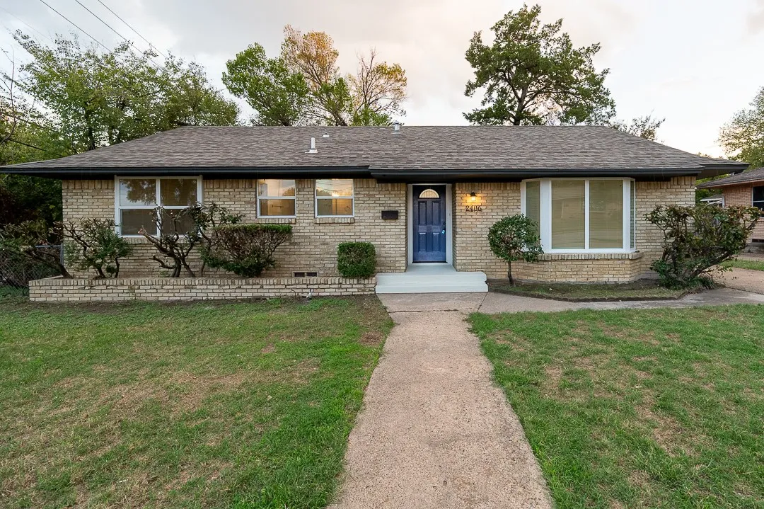 Single-story brick exterior featuring a low-pitched roof, central entryway, multi-pane windows, and a built-in front garden bed