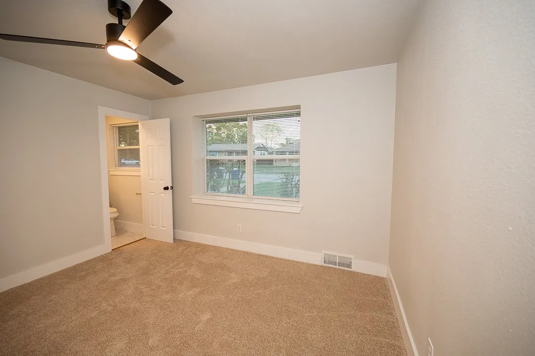 Room featuring neutral carpeting, matte black ceiling fan with integrated lighting, and a multi-pane window