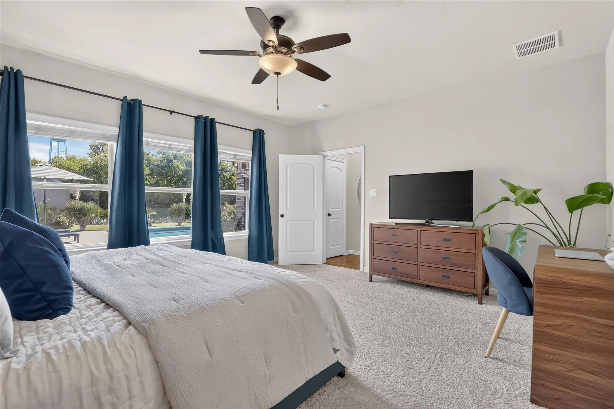 Bedroom featuring carpeted flooring, a ceiling fan with integrated lighting, and multiple windows providing natural light