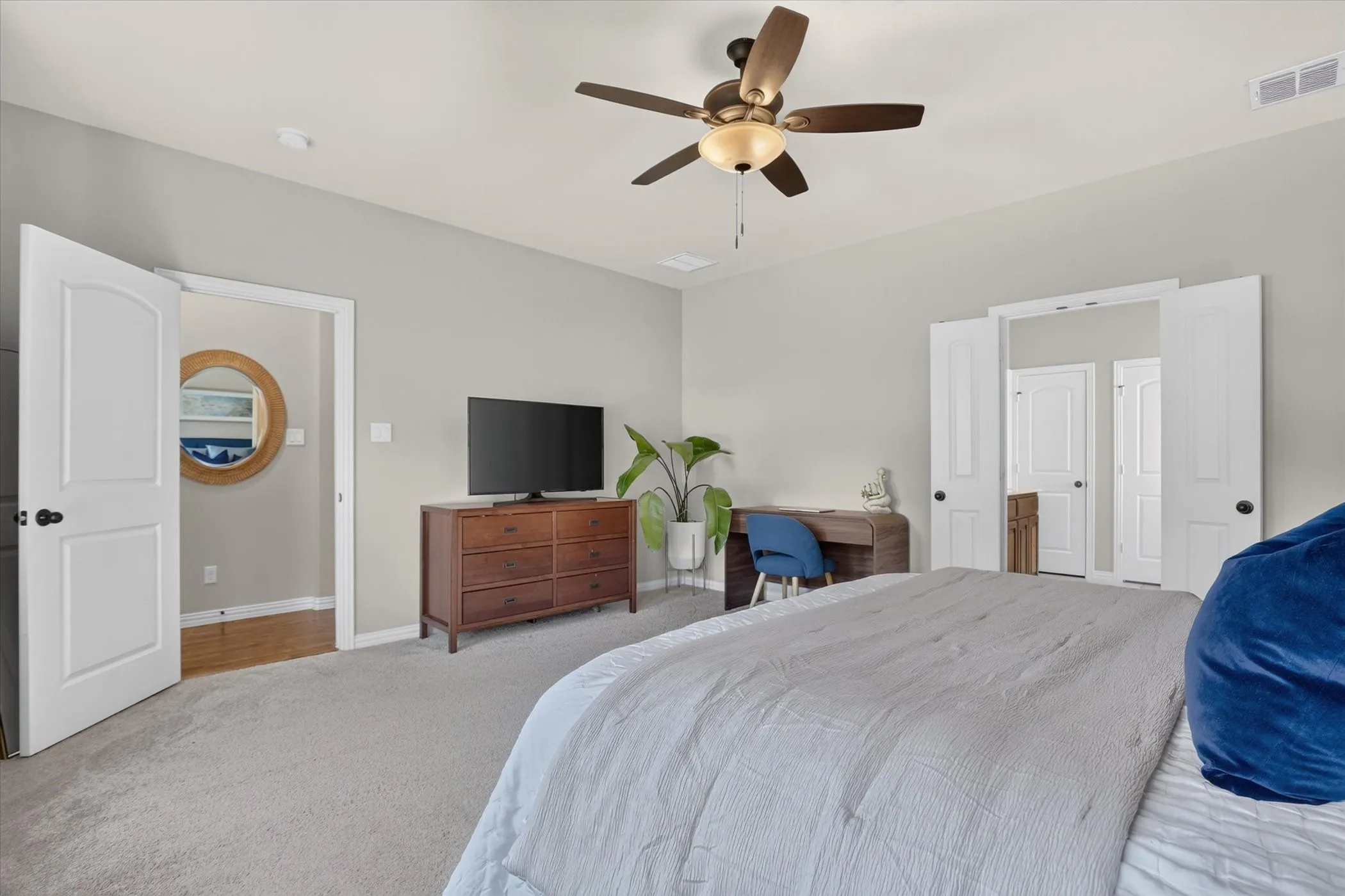 Neutral-toned interior featuring high ceilings, carpeted flooring, a multi-blade ceiling fan with integrated lighting, and white paneled doors