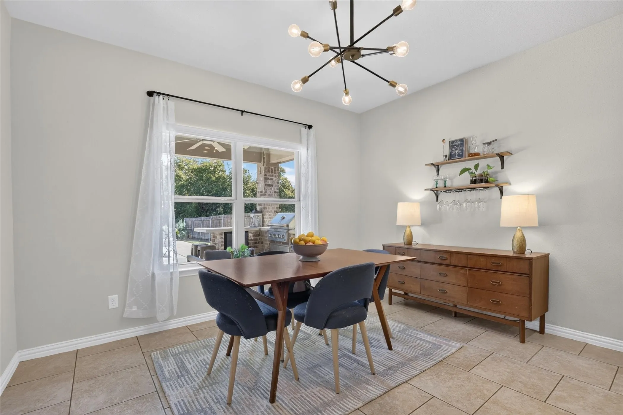 Multi-light contemporary chandelier, ceramic tile flooring, and wall-mounted shelving units