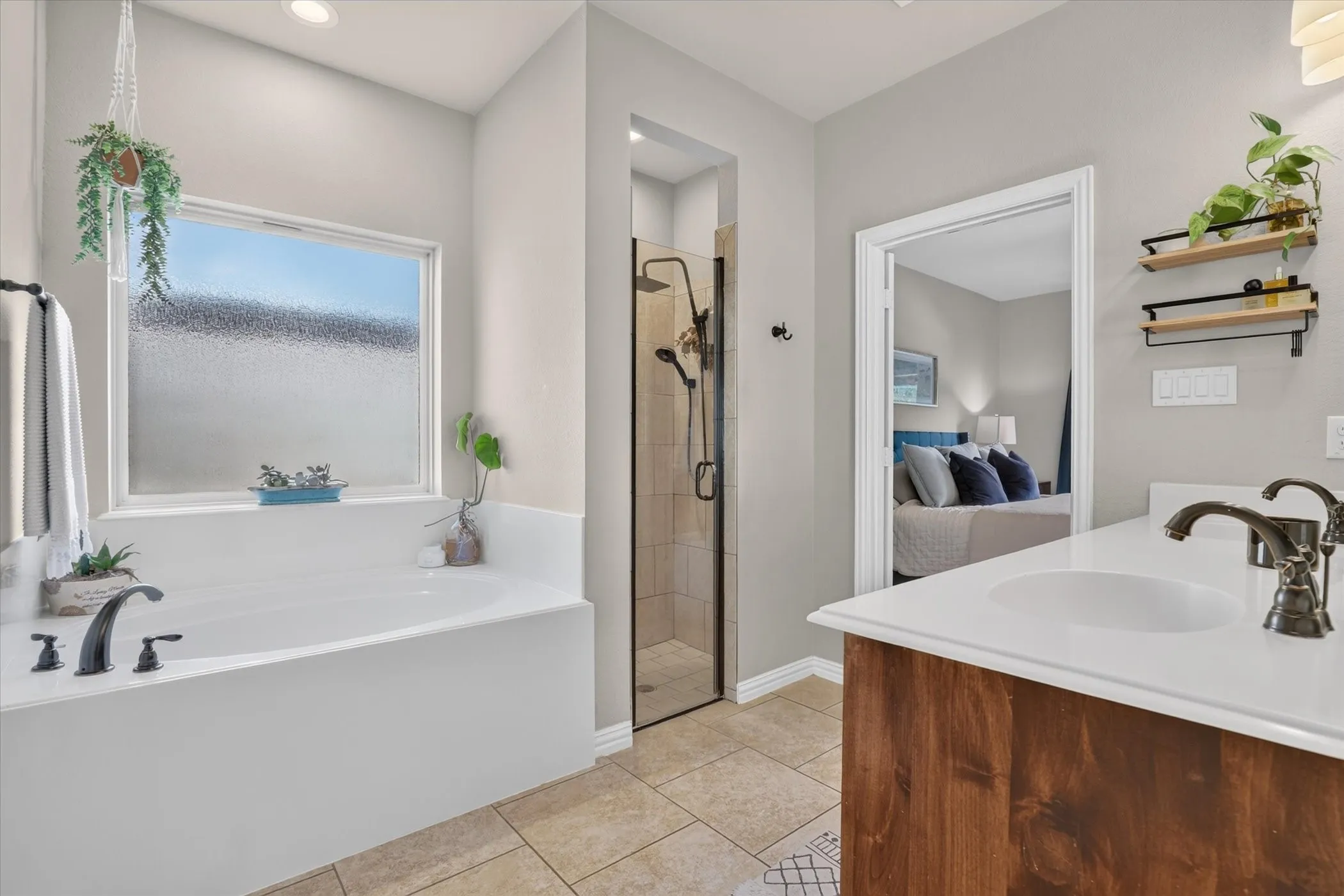 Bathroom featuring a deep soaking tub with a frosted window, a walk-in shower with tile surround, a wood-finish vanity, and a solid-surface countertop