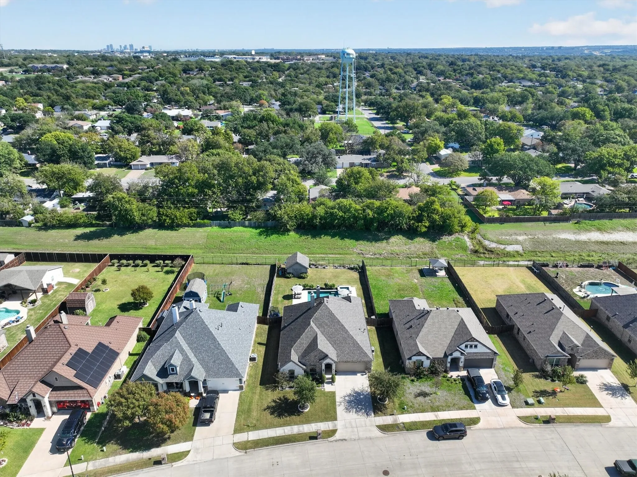 Aerial perspective of a suburban neighborhood featuring paved streets, established residential lots, mature trees, and local infrastructure