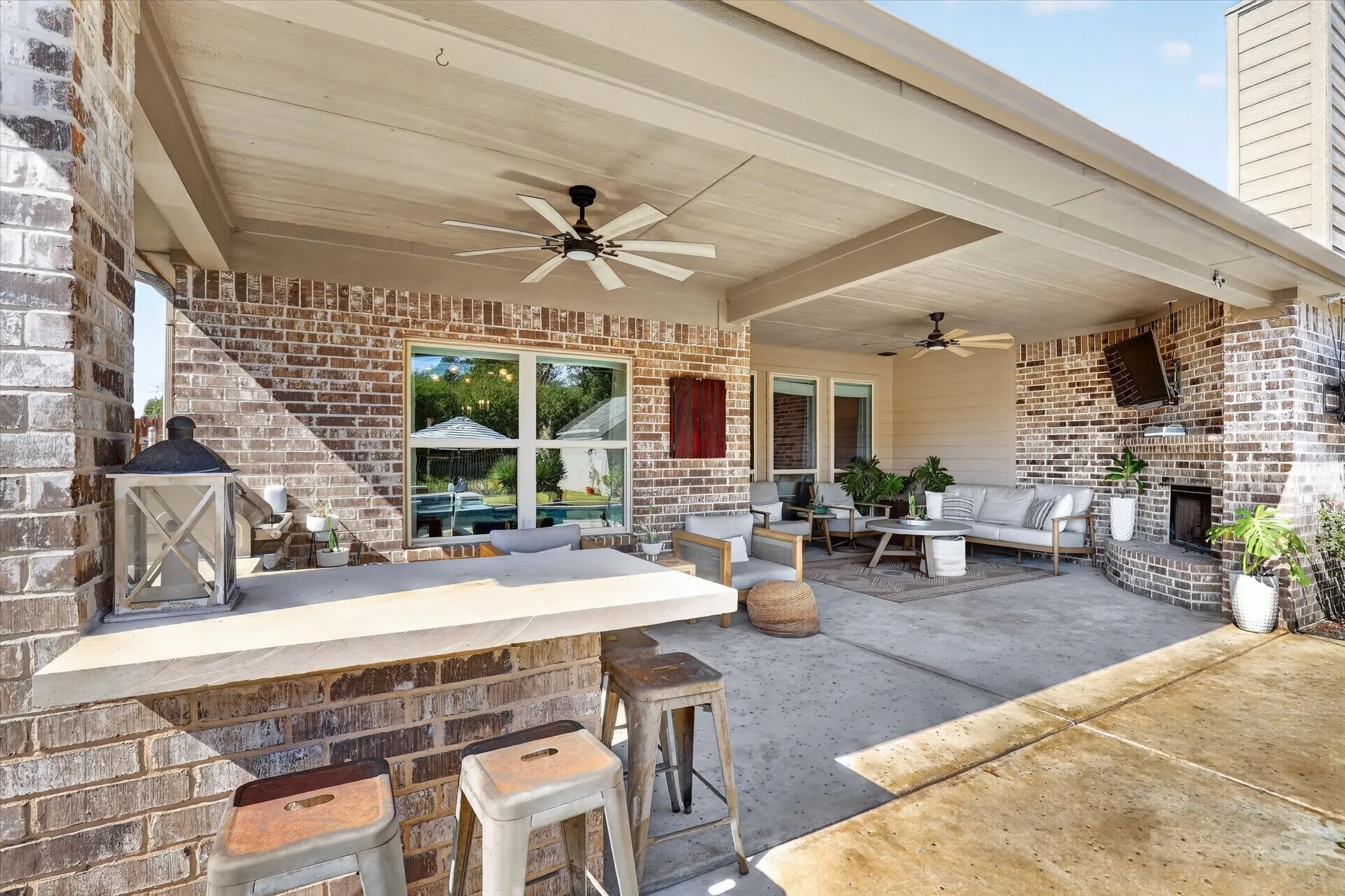 Covered patio featuring a brick exterior, built-in masonry fireplace, integrated service counter, and ceiling-mounted fans