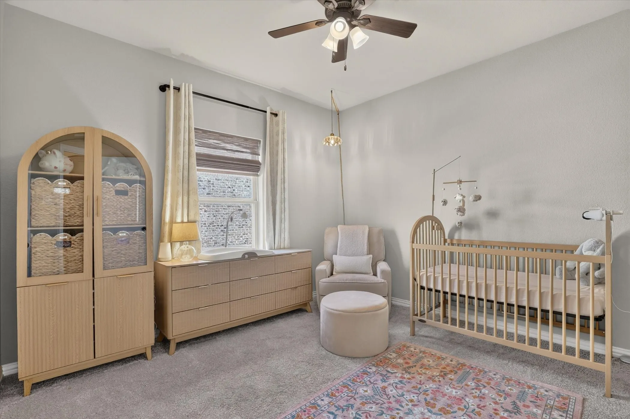 Neutral-toned room featuring plush wall-to-wall carpeting, a multi-pane window with custom drapery, and a ceiling-mounted light fixture with an integrated fan
