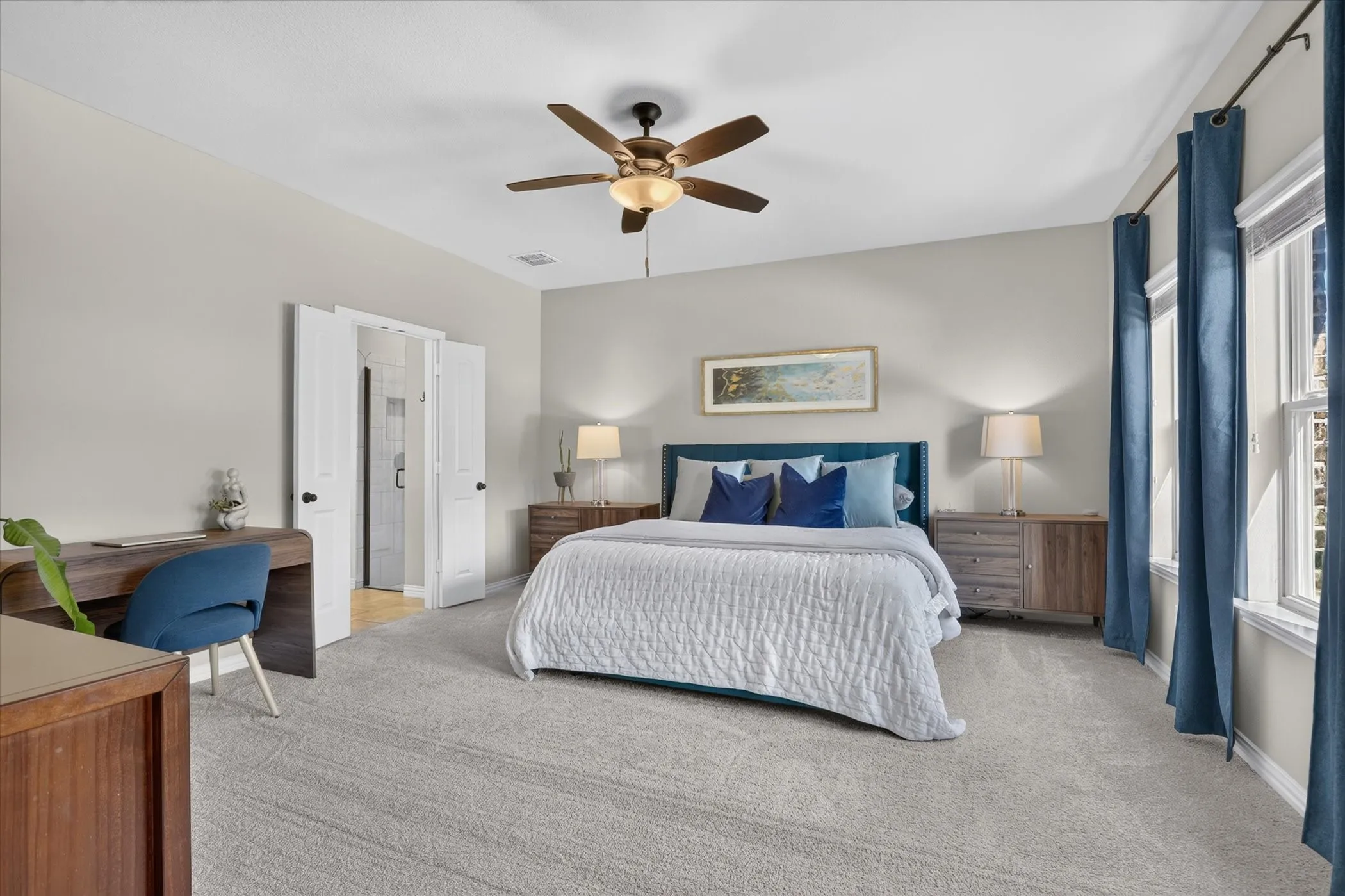 Neutral-toned bedroom featuring carpeting, a multi-blade ceiling fan with integrated lighting, double-panel doors, and windows with drapery hardware