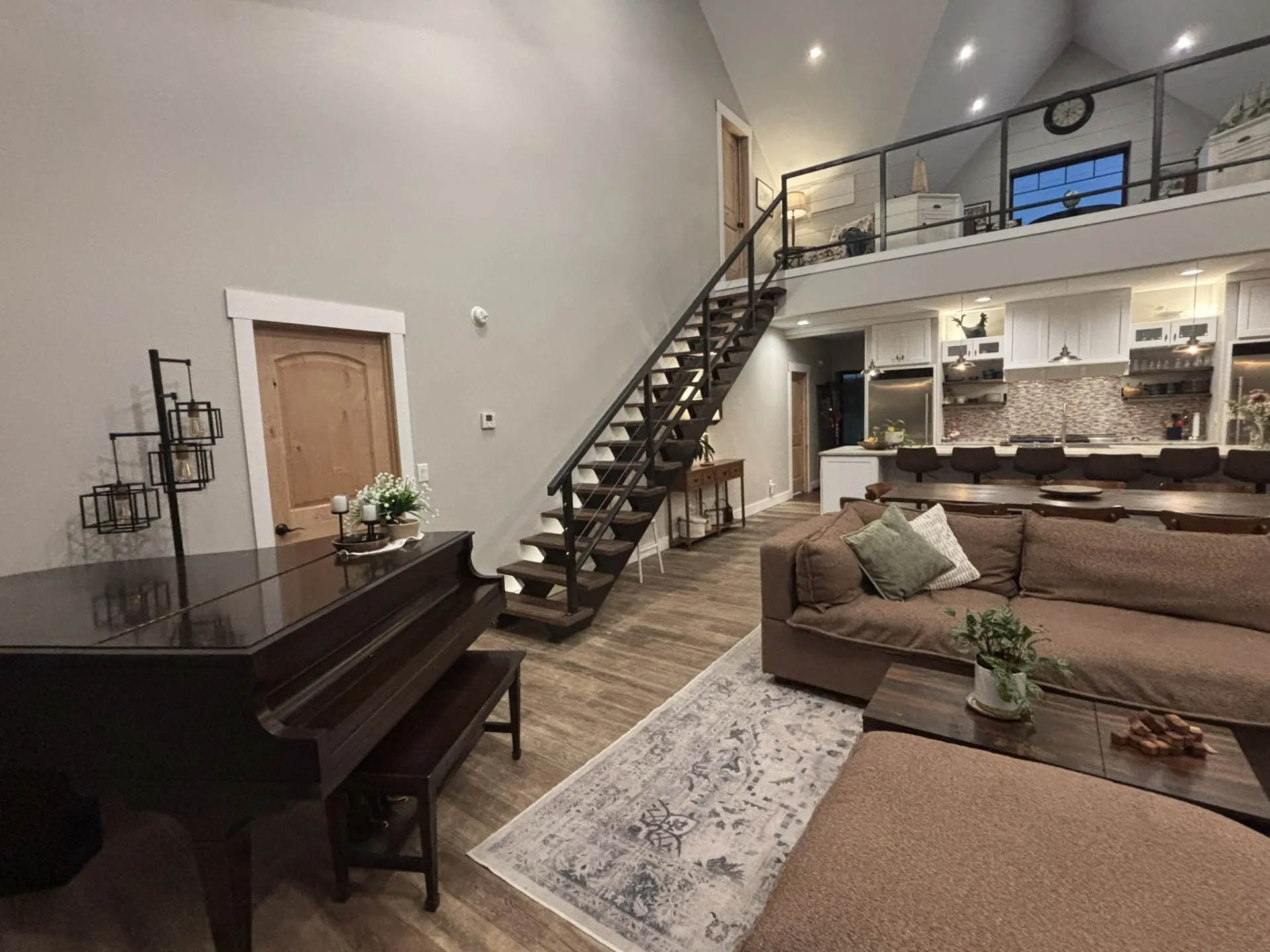 Vaulted ceilings, open staircase with iron railing, lofted overlook, wood-finish flooring, and recessed lighting